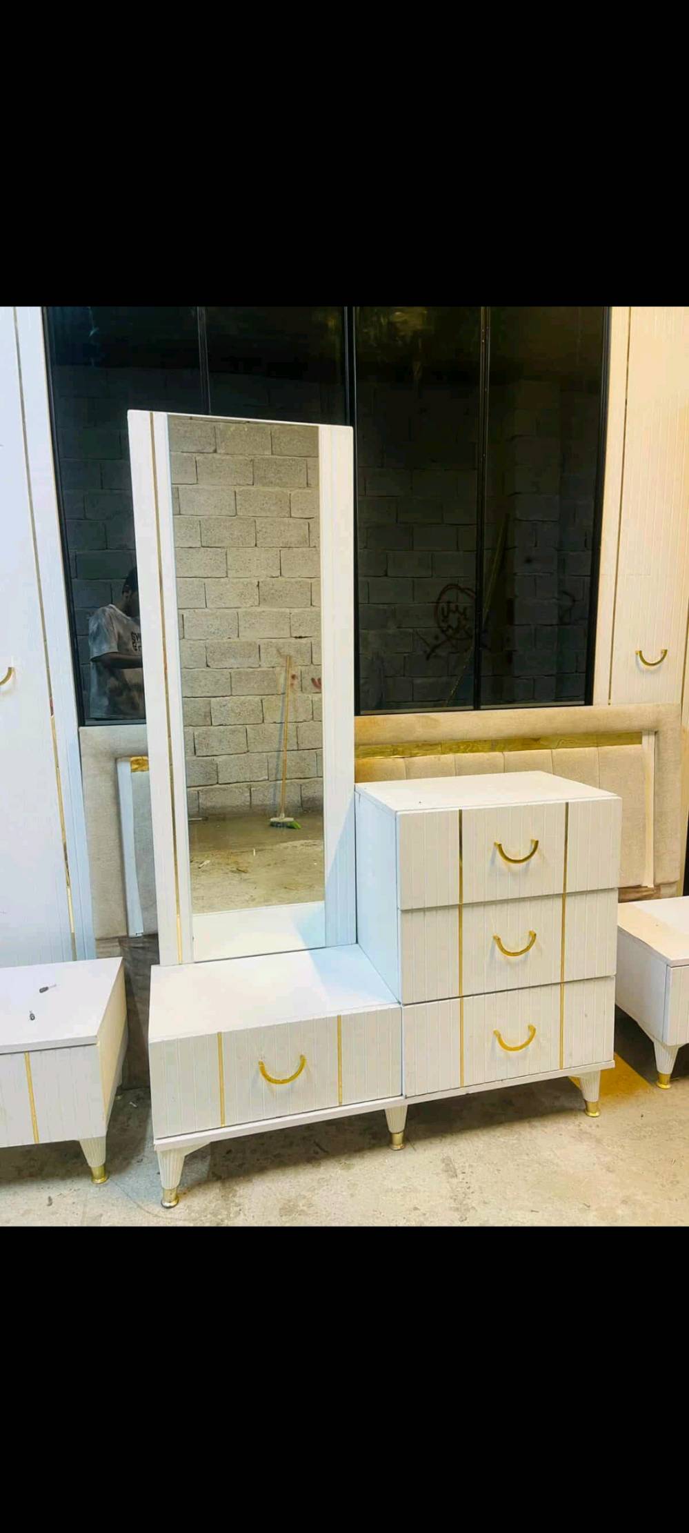 غرفة نوم كاملة تتضمن خزانة ملابس كبيرة بأبواب زجاجية مدهشة، قوة المرايا تزيد من الجمالية وتعطي إحساساً بالاتساع. يأتي مع الغرفة سرير مزود بظهر مبطن لمزيد من الراحة، بالإضافة إلى كومود صغيرة بأدراج عملية. تصميم كلاسيكي أنيق بلمسات ذهبية. مثالي لمن يبحث عن الرقي والوظائف معاً.