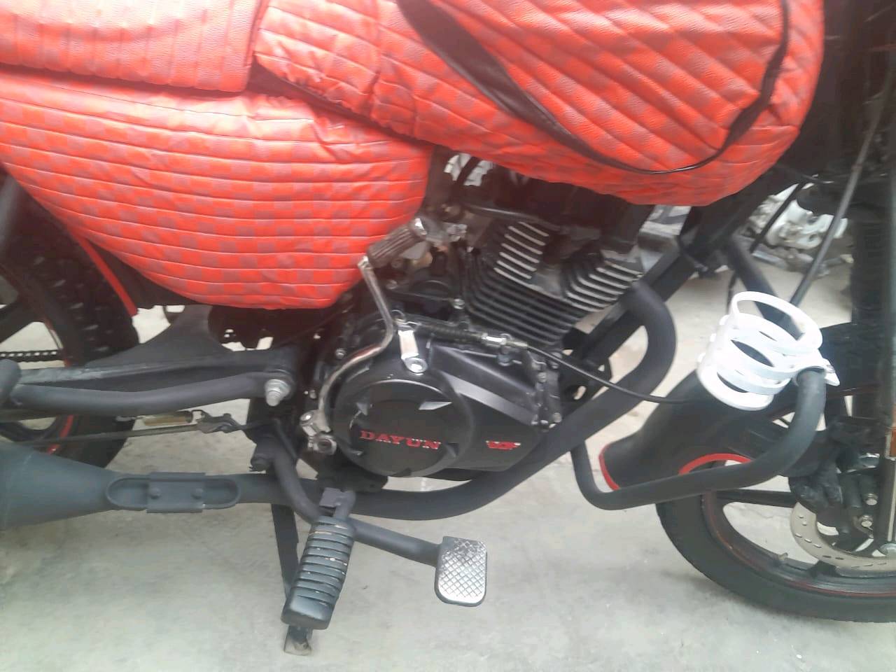 درّاجة نارية نوع دايون مع غطاء برتقالي خاص للتنجيد لمحافظة على المقاعد. بحالة ممتازة، مثالية للتنقل داخل المدينة والرحلات اليومية. العداد يظهر 23666 كيلومتر. متوفرة في بغداد وجاهزة للاستخدام المباشر.