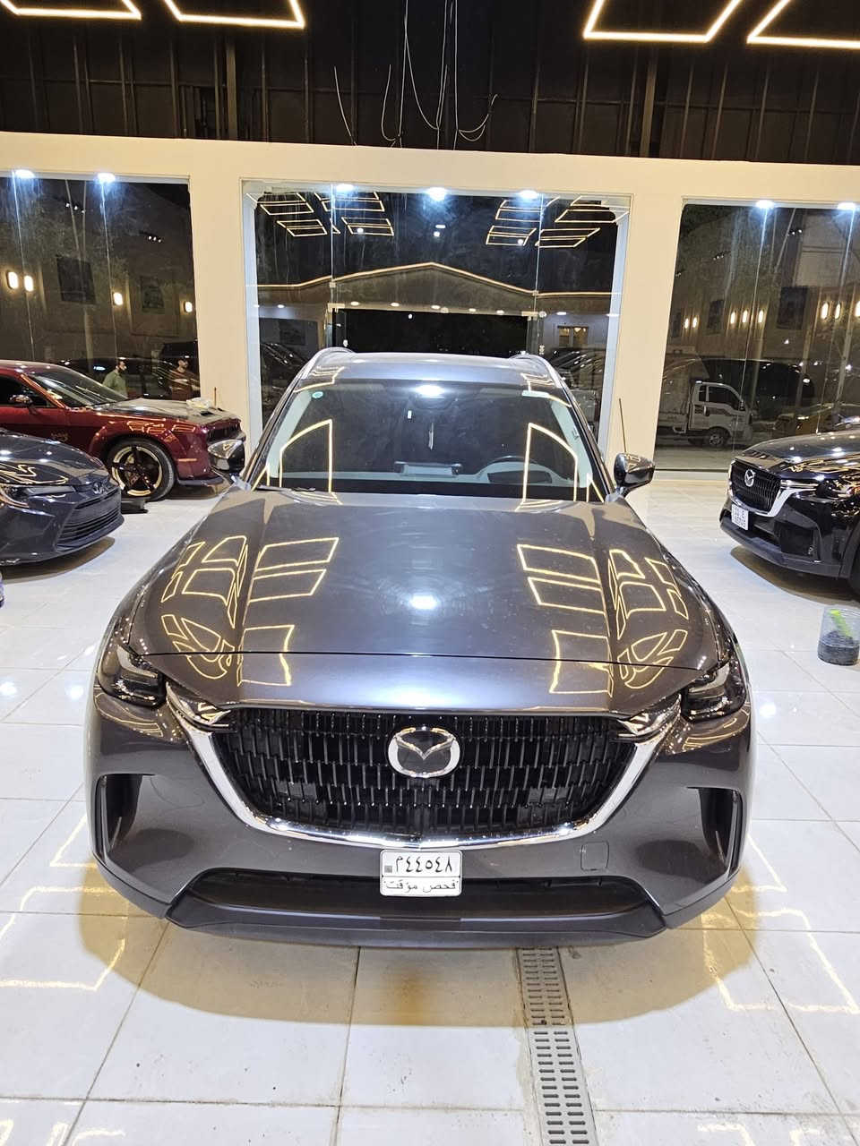 سيارة **مازدا CX-90 موديل 2024** بمحرك الـ 6 سلندر هجين (Mild Hybrid)  حيث تعتمد على محرك طولي ونظام دفع رباعي موجه للخلف لتحقيق أداء رياضي وفخم..
إليك أهم المواصفات التقنية والمميزات:
### 1. المحرك والأداء (e-Skyactiv G)
تتوفر بمحرك 6 أسطوانات متتالية (Inline-6) سعة 3.3 لتر مع شاحن تيربو، مدعوم بنظام هجين بسيط (48 فولت):
 * **القوة الحصانية:** تتوفر بخيارين حسب الفئة:
   * **الفئة القياسية:** 280 حصان وعزم دوران 450 نيوتن متر.
   * **الفئة العالية (S):** تصل إلى 340 حصان وعزم دوران 500 نيوتن متر (وهي أقوى سيارة إنتاجية من مازدا).
 * **ناقل الحركة:** أوتوماتيكي من 8 سرعات (جديد كلياً بدون محول عزم تقليدي لتوفير استجابة أسرع).
 * **نظام الدفع:** دفع كلي للعجلات (i-Activ AWD) بشكل قياسي.
 * **التسارع:** من 0 إلى 100 كم/ساعة في حوالي **5.8 إلى 6.5 ثانية** (حسب القوة).
### 2. استهلاك الوقود
 * تعتبر اقتصادية مقارنة بحجمها بفضل النظام الهجين، حيث تستهلك وسطياً حوالي **9.3 إلى 9.4 لتر لكل 100 كم**.
 * سعة خزان الوقود: **74 لتر**.
### 3. الأبعاد والمساحة
 * **الطول:** حوالي 5.1 متر، مما يجعلها سيارة SUV كبيرة بـ 3 صفوف من المقاعد.
 * **السعة:** تتوفر بخيارات 6 أو 7 أو 8 ركاب حسب التوزيع الداخلي.
 * **مساحة الأمتعة:** 608 لتر (خلف الصف الثالث) وتصل إلى 2025 لتر عند طي المقاعد.
### 4. التكنولوجيا والمقصورة الداخلية
 * **الشاشات:** شاشة مركزية كبيرة مقاس 12.3 بوصة تدعم Apple CarPlay و Android Auto لاسلكياً.
 * **النظام الصوتي:** يتوفر نظام Bose بـ 12 مكبر صوت في الفئات العليا.
 * **المواد:** استخدام جلود النابا، الأخشاب الطبيعية، وتطريزات مستوحاة من الفن الياباني التقليدي.
 * **ميزات إضافية:** فتحة سقف بانورامية، شاشة عرض على الزجاج الأمامي (Head-up Display)، وشحن لاسلكي.
### 5. أنظمة الأمان (i-Activsense)
 * نظام تثبيت السرعة التكيفي (الرادار).
 * نظام المساعدة في البقاء في المسار وتنبيه الخروج منه.
 * مكابح الطوارئ التلقائية مع رصد المشاة.
 * كاميرات 360 درجة مع خاصية "See-Through" لرؤية ما تحت السيارة أو حولها بوضوح.

**ملاحظة للمهتمين بالصيانة:** بما أنك تتابع تفاصيل المحركات بدقة، فإن هذا المحرك (Inline-6) مصمم ليكون متوازناً طبيعياً وأقل اهتزازاً من محركات الـ V6، وهو ما يعطي سلاسة تشبه محركات السيارات الألمانية الفاخرة.
ضررها  كفاله عامه تقرير مياه امطار تعمل وتسير
عداد المسافات ٤٠٠٠
للاستفسار معرض بلاتينيوم لتجارة السيارات  سامراء 
للاستفسار ***********
سيارة **مازدا CX-90 موديل 2024** بمحرك الـ 6 سلندر هجين (Mild Hybrid)  حيث تعتمد على محرك طولي ونظام دفع رباعي موجه للخلف لتحقيق أداء رياضي وفخم..

