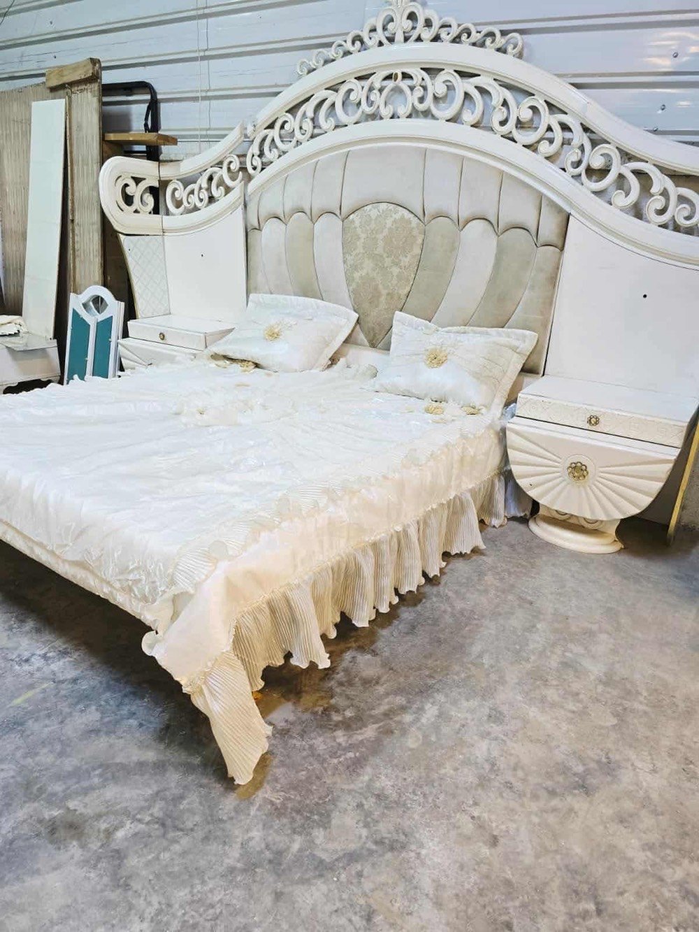 غرفة نوم فاخرة تصميم كلاسيكي، تتضمن سرير كبير مع خلفية منجدة بتفاصيل زخرفية جذابة باللون الأبيض، بالإضافة إلى خزانة ملابس مرايا وشيفونيرة مع أدراج واسعة. التصميم يتميز بالنقوش الكلاسيكية التي تضيف لمسة من الأناقة والرقي للغرفة. الأثاث بحالة جيدة ويضفي لمسة فاخرة على أي غرفة النوم.