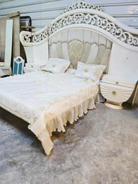 غرفة نوم فاخرة تصميم كلاسيكي، تتضمن سرير كبير مع خلفية منجدة بتفاصيل ز...