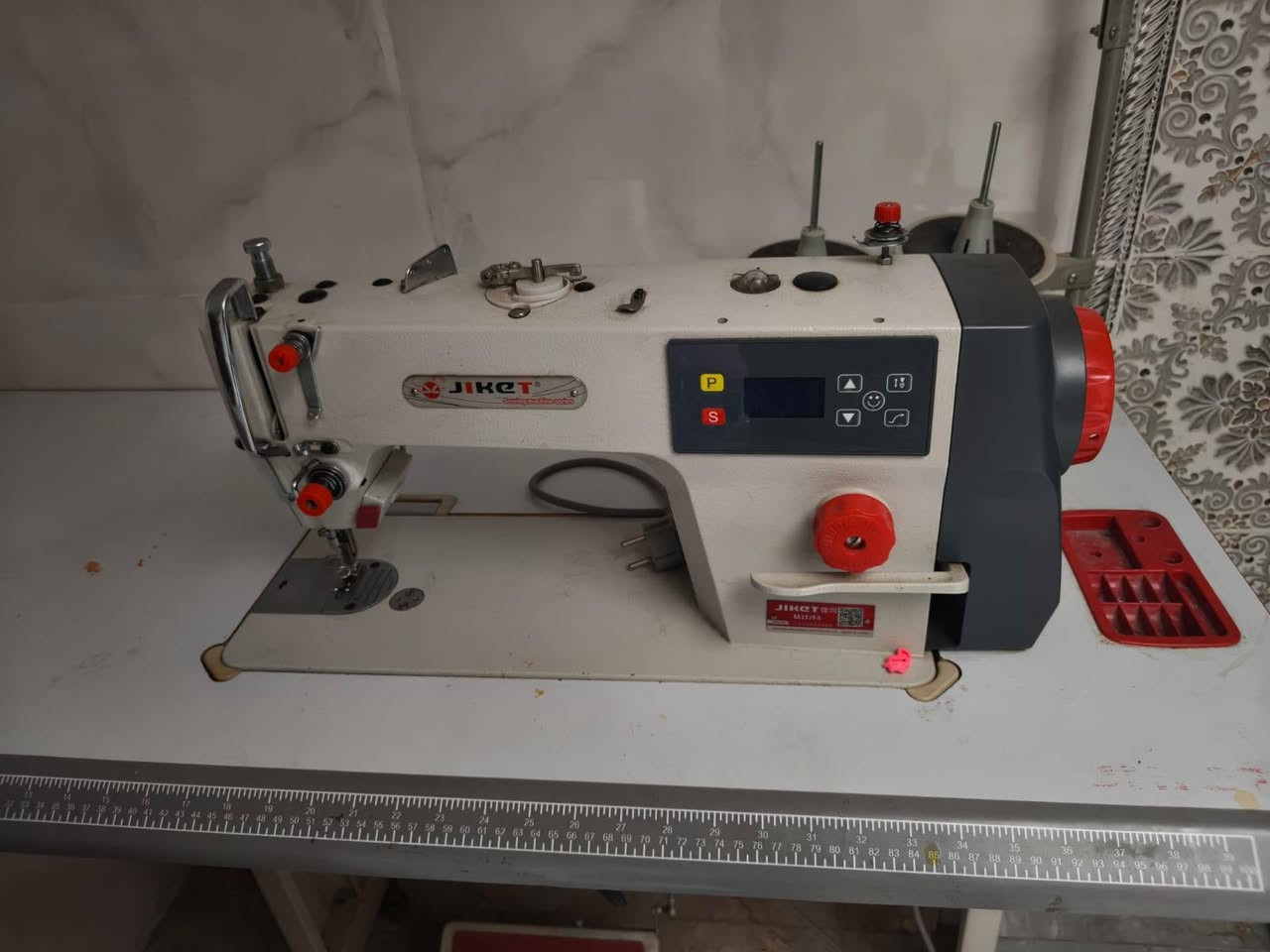 ماكينة خياطة صناعية درزة (Lockstitch) من شركة جاكيت (JIKET) موديل M2F (أو فئة الـ F4 المعدلة)، وهي ماكينة صناعية متطورة مخصصة للأقمشة الخفيفة والمتوسطة. 

أبرز مواصفات الماكينة ومميزاتها الأساسية تشمل:
⚙️ المواصفات والميزات الأساسية
ماتور داخلي (سيرفو) سحب مباشر (Direct Drive): الماتور مدمج داخل رأس الماكينة مباشرة، مما يجعلها كاتمة للصوت تماماً ومستقرة دون اهتزازات أثناء العمل. 

توفير عالي للطاقة: يستهلك المحرك طاقة منخفضة جداً ويوفر ما يقارب 60% إلى 70% من استهلاك الكهرباء مقارنة بالمكائن التقليدية ذات الماتور الخارجي الضخم. 

لوحة تحكم رقمية (شاشة شريطية): تتيح للمستخدم ضبط الخيارات بسهولة فائقة ومنها:
تحكم بالسرعة: زيادة أو تقليل سرعة الغرز بما يتناسب مع مهارة الخياط ونوع القماش.
تحكم بموضع الإبرة (Positioner): تحديد وضعية توقف الإبرة تلقائياً عند التوقف عن الخياطة (إما داخل القماش لتسهيل الدوران، أو مرتفعة للأعلى لسحب القماش). 

منظم طول الغرزة: بكرة ميكانيكية حمراء لتعديل المسافة بين الغرز بدقة
إضاءة LED مدمجة: تحتوي على ضوء قوي وموفر عند منطقة الإبرة لتسهيل الرؤية وتخفيف إجهاد العين أثناء العمل. 

نظام تزييت أوتوماتيكي: مضخة زيت داخلية تضمن وصول التشحيم لكافة أجزاء الماكينة تلقائياً لزيادة عمرها الافتراضي. 

السعر 450 الف استعمال جدا قليل 

عنواني بغداد الحسينية 

مبايل ***********

