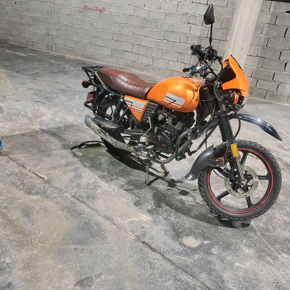 دراجة نارية برتقالية اللون بحالة جيدة جداً، مثالية للاستخدام اليومي والتنقل. تحتوي على حقيبة تخزين خلفية كبيرة، ممتازة لتوصيل الطرود أو استخدامات المتعددة. تمتاز بمقعد مريح وتصميم عصري. السعر منافس ومناسب لمن يبحث عن أداء عالي بأسعار معقولة.