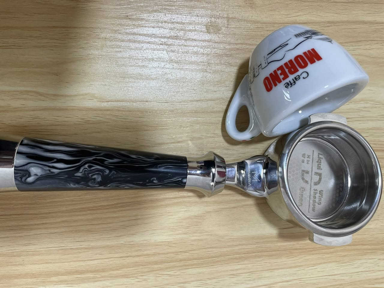 (Bottomless Portafilter) مخصص لآلات الإسبريسو الاحترافية، وهو من إنتاج شركة MUVNA المعروفة في أكسسوارات القهوة المختصة.

إليك تفاصيل ومواصفات هذه القطعة بناءً على الصور:
1. التصميم والمظهر
 المقبض (Handle): يأتي بتصميم مميز جداً بنقشة رخامية متموجة باللونين الأسود والأبيض (Resin/Acrylic swirl)، مع نهايات معدنية مصقولة من الكروم اللامع تعطي ثقلاً وتوازناً أثناء الاستخدام.

 الرأس (Head): مصنوع من المعدن المقاوم للصدأ (Stainless Steel) عالي الجودة والمصقول بعناية.
 العلامة التجارية: شعار MUVNA محفور بوضوح على الجزء المعدني الواصل بين المقبض والرأس.

2. السلة (Basket) المرفقة
 البورتافلتر يأتي ومعه سلة ترشيح احترافية مدمجة.
 تسمى هذه السلة في هذا الإصدار بـ "Liquid Demon" أو "Wing Shadow" كما هو محفور في قاع السلة داخلياً.
 تتميز السلة بنمط ثقوب دقيق جداً (توزيع متناسق يشبه خلايا النحل في الأطراف)، وهو تصميم مخصص لتحسين التدفق (High-flow) لضمان استخلاص متساوٍ لكامل كعكة القهوة (Puck) واستخراج نكهات أكثر وضوحاً وقوام غني.


**إذا كنت صاحب هذا الإعلان وتريد حذفه لأي سبب، رجاءا أرسل رسالة إلى الدعم الفني**