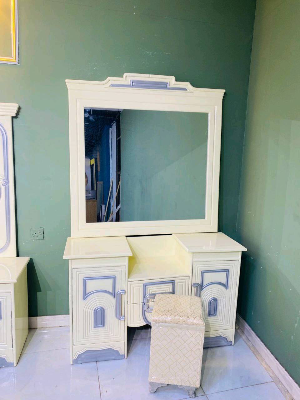 غرفة نوم فاخرة بتصميم كلاسيكي جذاب تتميز بمظهر أنيق وفخم. تضم سرير واسع ودولاب ملابس كبير مع مرايا، بالإضافة إلى طاولة زينة ودواليب جانبية بنفس التصميم. الخامات المستخدمة تعطي مظهر دافئ ومريح، مثالي لإضفاء لمسة من الفخامة في غرفة نومك.