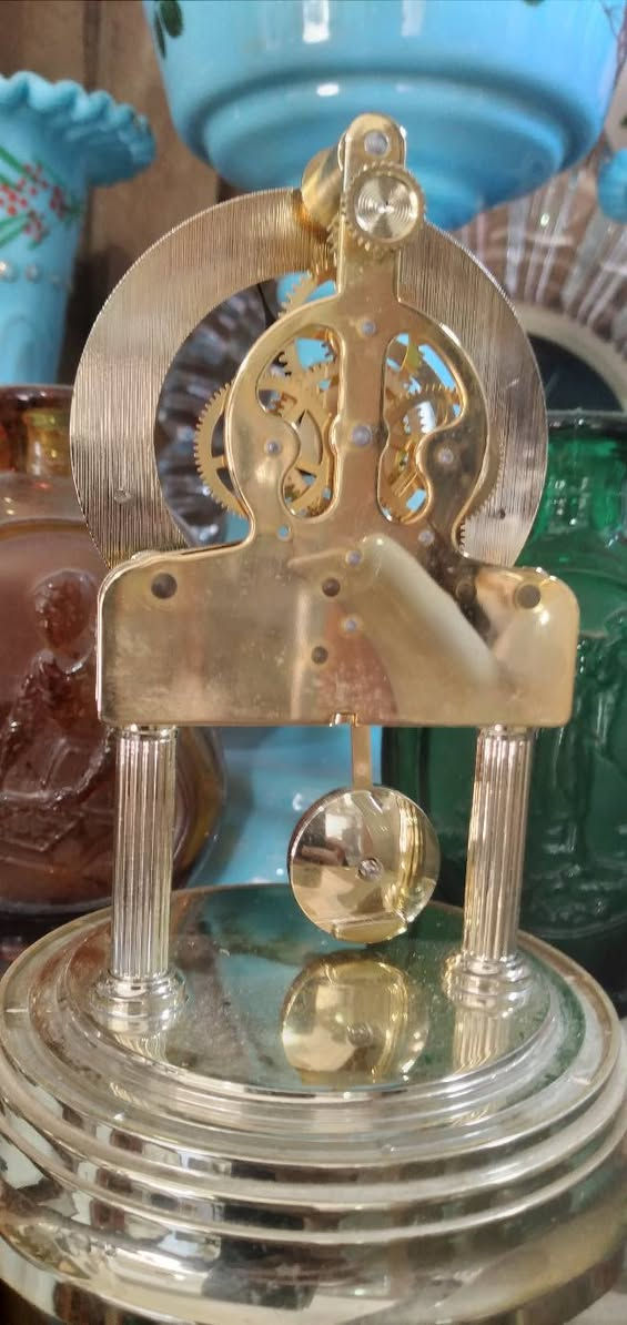 ***********
ساعة طاولة عتيقة من طراز Kundo Quartz Torsion، وتتميز بغطاء زجاجي واقٍ.تحتوي الساعة على حركة مرئية تعمل بالبطارية، مع قرص ذو أرقام رومانية وشعار  ريذم
