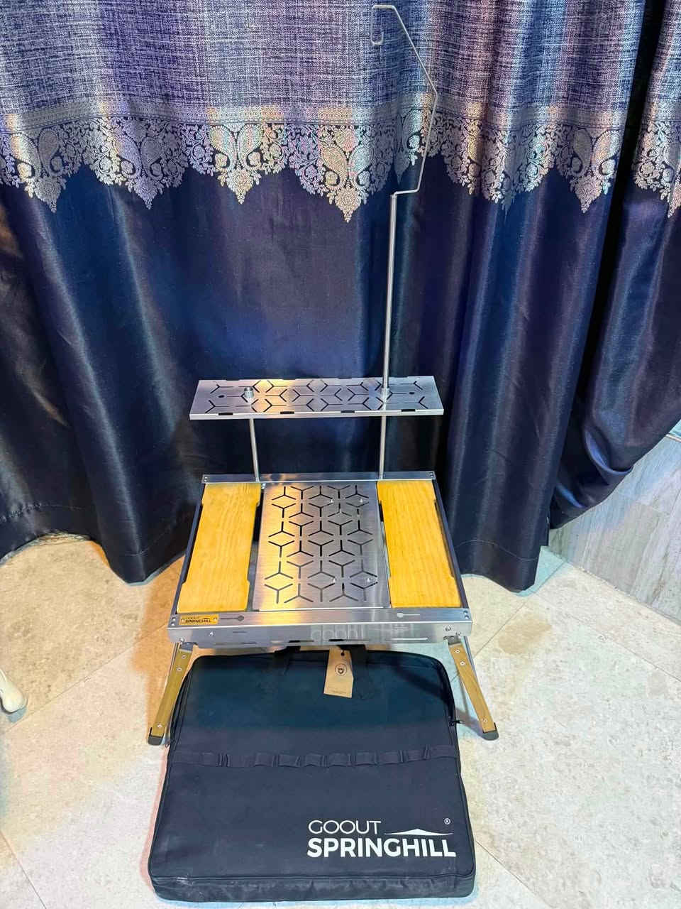 السلام عليكم للبيع طاولة تخييم من إنتاج العلامة التجارية Goout Springhill. 
تتميز هذه الطاولة بتصميم ذكي وقابل للتخصيص بالكامل ليناسب احتياجات الطهي والجلوس في الهواء الطلق.
الميزات والمكونات الرئيسية للطاولة:نظام موديولي (IGT Compatible): يتيح لك فك وتركيب الألواح العلوية حسب الحاجة. يمكنك إزالة اللوح المعدني الأوسط وتركيب موقد غاز متوافق مكانه للطهي
حامل الفانوس العلوي: مزودة بعمود معدني طويل يمتد للأعلى مع خطاف مخصص لتعليق فوانيس الإضاءة أو أدوات المطبخ.
رف علوي إضافي: يوفر مساحة تخزين علوية مدمجة لوضع التوابل، الأكواب، أو أدوات الطهي الصغيرة.
حقيبة تخزين مخصصة: تأتي الطاولة مع حقيبة حمل سوداء متينة مطبوع عليها شعار العلامة التجارية لتسهيل نقلها وحمايتها أثناء التنقل. مصممة لتكون متعددة الوظائف وقابلة للتعديل.
الأبعاد : 
الارتفاع الإجمالي 38 سم من الأرض حتى سطح الطاولة.
عرض السطح العلوي: 52.5 سم.الطول الإجمالي (بين الأرجل): 71 سم.
العمق: 42 سم.
مواصفات الرف العلوي والملحقات:
ارتفاع الرف الإضافي: 21 سم فوق سطح الطاولة.
ارتفاع حامل الفانوس/الإضاءة: 66.5 سم.
تواصل خاص او *********** واتساب
