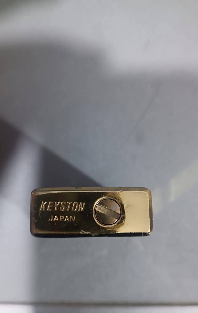 وضع AI
هذه القطعة عبارة عن قداحة  غاز عتيقة (Vintage) من العلامة التجارية اليابانية Keyston. 

أهم تفاصيل ومواصفات القطعة

بلد المنشأ: اليابان (Japan) كما هو محفور في الأسفل.

الفترة الزمنية: تعود هذه القداحات غالباً إلى فترة السبعينيات من القرن الماضي (حوالي عام 1970 وما قبله).

التصميم: تتميز بهيكل كلاسيكي مستوحى من تصاميم الماركات الفاخرة مثل S.T. Dupont، ومطلية باللون الذهبي.

نوع الوقود: تعمل بغاز البيوتان (Butane Gas)، ويظهر في الأسفل برغي الصمام المخصص لتعبئة الغاز وتبديل حجر الولاعة (الفتيل). 
تُصنّف هذه الولاعة اليوم كقطعة "أنتيك" مميزة يفضلها هواة جمع المقتنيات القديمة.


**إذا كنت صاحب هذا الإعلان وتريد حذفه لأي سبب، رجاءا أرسل رسالة إلى الدعم الفني**