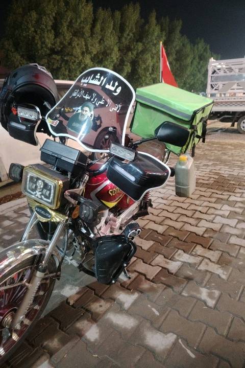 دراجة نارية للبيع، لونها أحمر مع تصميم رياضي وجذاب. تتضمن صندوق أخضر خلفي عملي لحفظ الأغراض. مثالية للتنقل في المدينة أو التوصيل. الواجه الأمامية مزودة بحاجب شمس لحماية العينين أثناء القيادة. مناسبة لمن يبحث عن وسيلة نقل اقتصادية وسهلة التعامل.