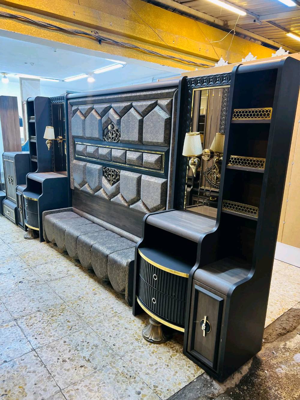 غرفة نوم مودرن وجديدة للبيع، تتميز بتصميم راقي وأنيق بلون رمادي مع لمسات ذهبية. تحتوي الغرفة على خزانة ملابس واسعة مع مرايا، وتسريحة مع أدراج ووحدات تخزين متعددة بالإضافة إلى طاولات جانبية بتصميم جمالي لتكمل الديكور. تناسب مختلف الأذواق وتضيف لمسة من الفخامة لأي منزل.