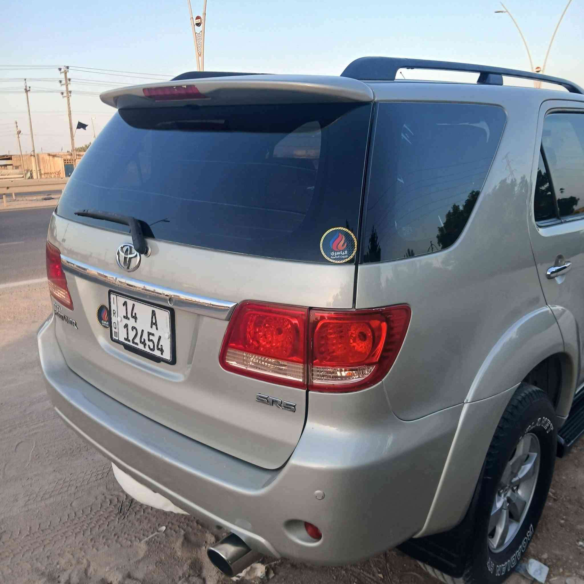 السيارة الظاهرة في الصورة "1000372575.jpg" هي تويوتا فورتشنر (Toyota Fortuner) من الجيل الأول (تحديداً الموديلات بين 2005 و 2008 قبل التحديث الأول). وهي سيارة SUV مخصصة للمهام الشاقة تعتمد على شاسيه "تويوتا هايلوكس".
إليك المواصفات الكاملة والعامة لهذا الجيل:

​1. المحرك والأداء (تأتي بخيارين رئيسيين للمحركات)

​المحرك الأول (٦ سلندر): سعة 2.7 لتر (2TR-FE) بقوة حوالي 158 حصان.

​المحرك الثاني (6 سلندر - V6): سعة 4.0 لتر (1GR-FE) بقوة حوالي 235 حصان (وهو الأكثر انتشاراً للفئات العالية).

​ناقل الحركة: آلي (أوتوماتيك) من 4 أو 5 سرعات، أو يدوي من 5 سرعات.

​نظام الدفع: دفع رباعي مستمر (4WD) مع ناقل حركة يدوي إضافي لتغيير وضعيات الدفع (الدبل الثقيل والخفيف)، وتتوفر ببعض الأسواق بدفع ثنائي خلفي فقط.

​2. الأبعاد والتصميم الخارجي

​النوع: سيارة رياضية متعددة الاستخدامات (SUV) متوسطة الحجم بـ 5 أبواب.

​المظهر الأمامي (كما في الصورة): شبك أمامي بلمسات كروم، ومصابيح أمامية هالوجين كبيرة، وكشافات ضباب سفلية مدمجة في المصد.

​الإضافات الظاهرة في الصورة: تم تركيب مصد حماية أمامي معدني (دعامية) لحماية الواجهة، وقضبان سقفية (Roof Rails).

​3. المقصورة والراحة الداخلية

​السعة: تتسع لـ 7 ركاب (ثلاثة صفوف من المقاعد).

​التكييف: نظام تكييف قوي جداً (هوائي مزدوج أمامي وخلفي لتغطية الصفوف الثلاثة).

​المقاعد: مخمل (قماش) في الفئات القياسية، وجلد في الفئات الكاملة (المواصفات العالية).

​4. الأمان والسلامة

​وسائد هوائية أمامية (Airbags) للسائق والراكب الأمامي.

​نظام فرامل مانع للانغلاق (ABS).

​هيكل صلب مخصص للطرق الوعرة وتحمل الصدمات.

​هل تود معرفة تفاصيل محددة حول فئة معينة من هذا الموديل أو قطع الغيار الخاصة به؟

السيارة الظاهرة في الصورة "1000372575.jpg" هي تويوتا فورتشنر (Toyota Fortuner) من الجيل الأول (تحديداً الموديلات بين 2005 و 2008 قبل التحديث الأول). وهي سيارة SUV مخصصة للمهام الشاقة تعتمد على شاسيه "تويوتا هايلوكس".
***********
السعر المطلوب ١٣٧٠٠٠ الف دولار مع المجال
