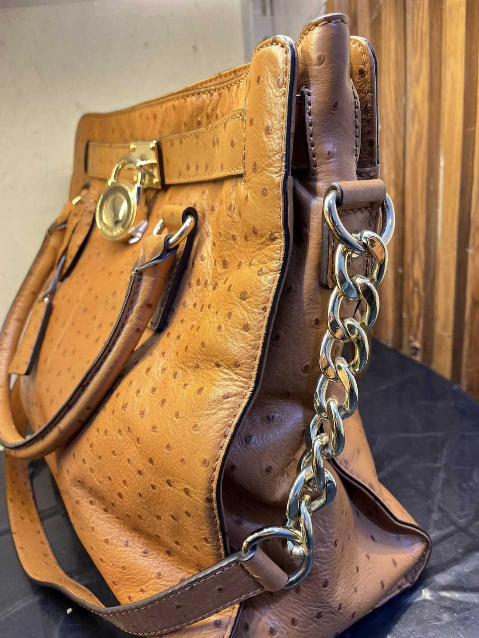 حقيبة اليد هذه هي حقيبة يد (توت) هاميلتون من مايكل كورس بنقشة النعام البارزة. تتميز الحقيبة بلونها البرتقالي المائل للسمرة وتفاصيلها الذهبية، بما في ذلك القفل المتدلي وحزام السلسلة الاختياري. 

العلامة التجارية: مايكل كورس (Michael Kors)
الموديل: هاميلتون (Hamilton)
الخامة: جلد بنقشة النعام البارزة
اللون: برتقالي أو تان (Orange/Tan)
الميزات: قفل ذهبي مميز، ومقابض علوية، وحزام كتف سلسلة اختياري
الحالة: مستخدمة استعمال خفيف – نظيفة وبحالة جيدة
• المناسبة: يومي، دوام، مناسبات خفيفة، سفر
• السعة: متوسطة – تشيل أغراض أساسية (محفظة، موبايل، مفاتيح، عطر)
للتواصل خاص : *********** فقط واتساب
