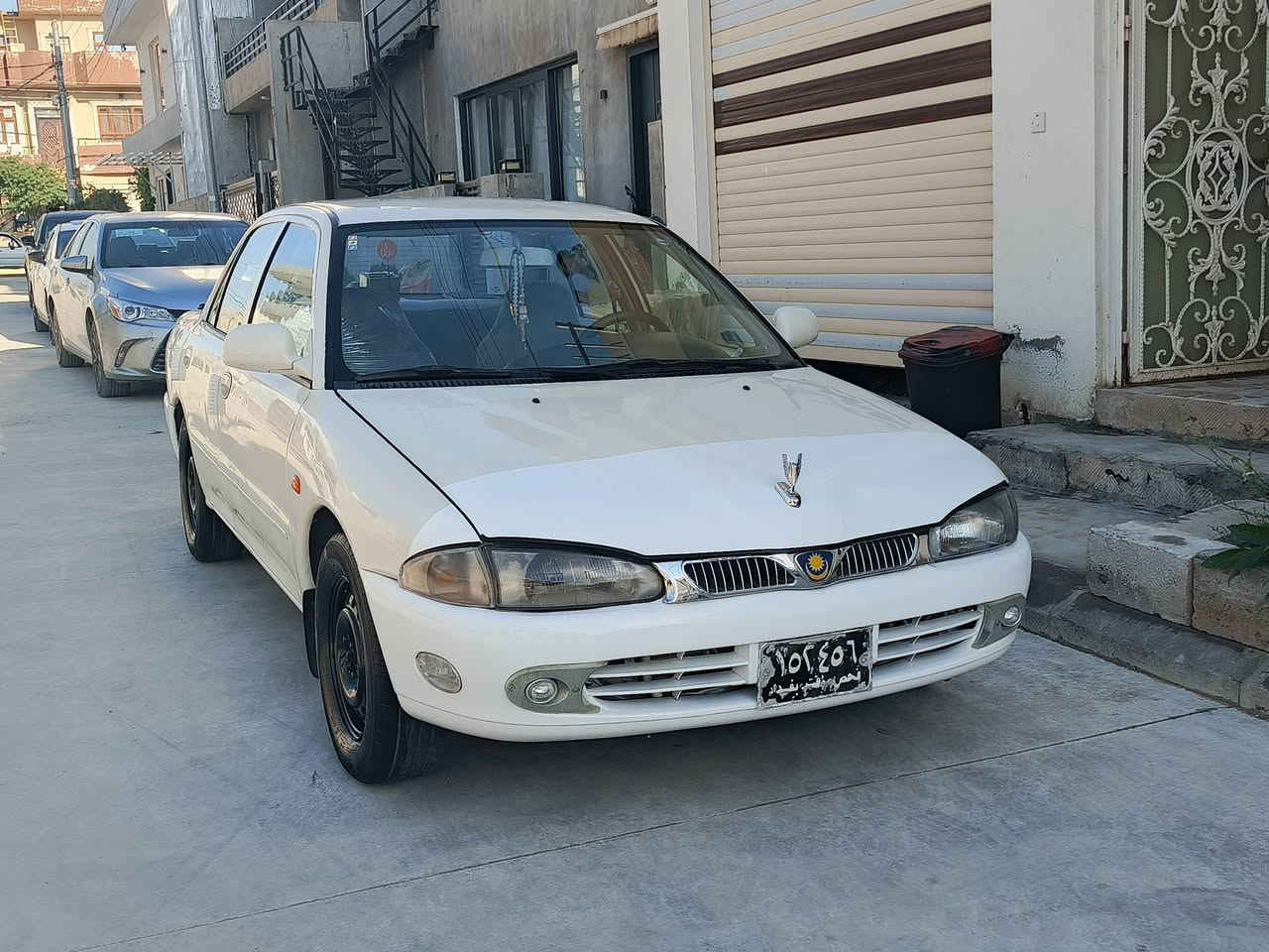 سەرەتا بەناوی خوای گەورەو مهرەبان
پڕۆتۆن مۆدیلی 2004
گێڕ ئۆتۆماتیکە
ئاڕم  پلاســــتیـــکی بێ کێشیە
ئاڕم و ئەوەلیات بـەشەرت
گـێڕ و مـەکــینە بەشەرتی فیتەر
چــوار تایـــەو ویـلی لۆکی لەژێرە
تـند و تۆڵــی و تەقەوڕەقە بەشەرت
سەیارەکە دەعـم و لێدراوی هیـچ نیە
کارەبایی هەمـوو گیانـــی ئیش دەکات
دەعامــی بــۆ دعامـــی بـەشـەرت 
شـــوێـــن : ســلێمانــی 
ژم : ***********
