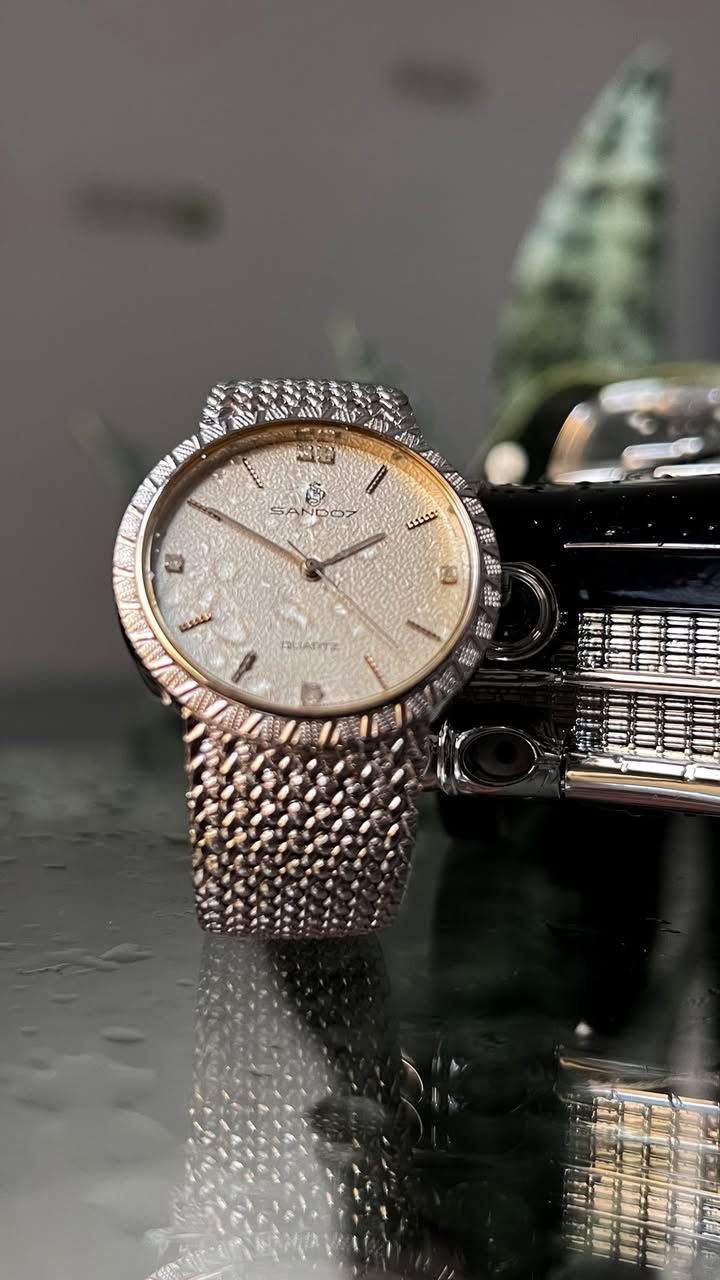 Sandoz
(ساندوز) - ماركة سويسرية غنية عن التعريف.
• الحركة: Quartz (كوارتز) دقيقة جداً.
• القطر: 32 مم (حجم مثالي، انسيابي ومريح جداً على المعصم).
• الميناء (Dial): يتميز بملمس "حبيبي" (Textured) بلون كريمي/فضي يضفي عمقاً وفخامة، مع فصوص أنيقة عند علامات الساعة.
• الإطار (Bezel): إطار مشغول بنقشة هندسية مميزة تعكس الضوء بجمالية عالية.
• السوار (Strap): سوار معدني بنقشة "Mesh" (حصير) ناعمة جداً ومرنة، توفر راحة تامة أثناء الارتداء.
• الظهر: ستانلس ستيل محفور عليه شعار الشركة ورقم الموديل (BM-1020).
• الحالة: الساعة بحالة ممتازة كما هو واضح في الصور، وتعمل بكفاءة تامة.
🔸للأستفسار أكثر يرجى التواصل خاص🔻


**إذا كنت صاحب هذا الإعلان وتريد حذفه لأي سبب، رجاءا أرسل رسالة إلى الدعم الفني**