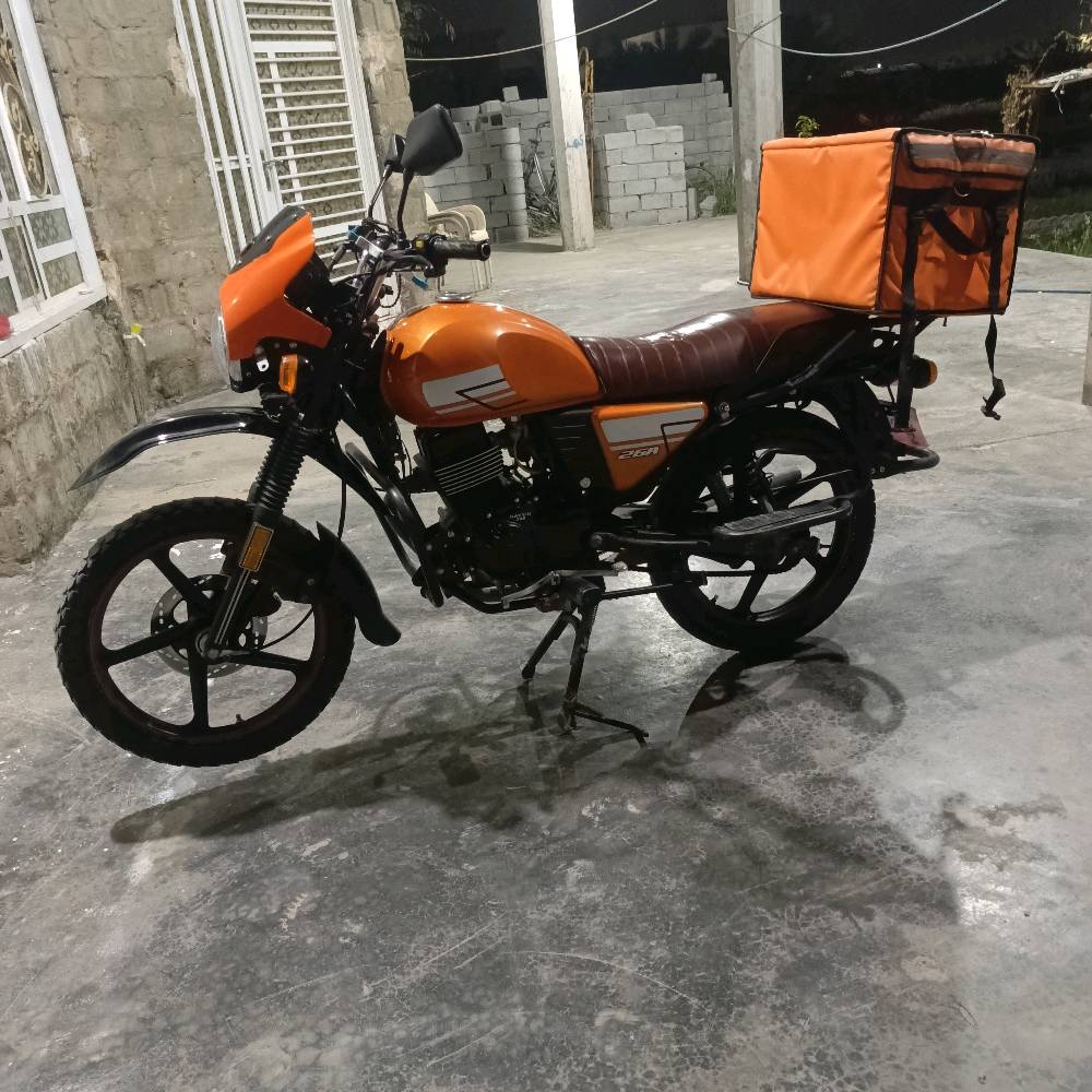 دراجة نارية برتقالية اللون بحالة جيدة جداً، مثالية للاستخدام اليومي والتنقل. تحتوي على حقيبة تخزين خلفية كبيرة، ممتازة لتوصيل الطرود أو استخدامات المتعددة. تمتاز بمقعد مريح وتصميم عصري. السعر منافس ومناسب لمن يبحث عن أداء عالي بأسعار معقولة.