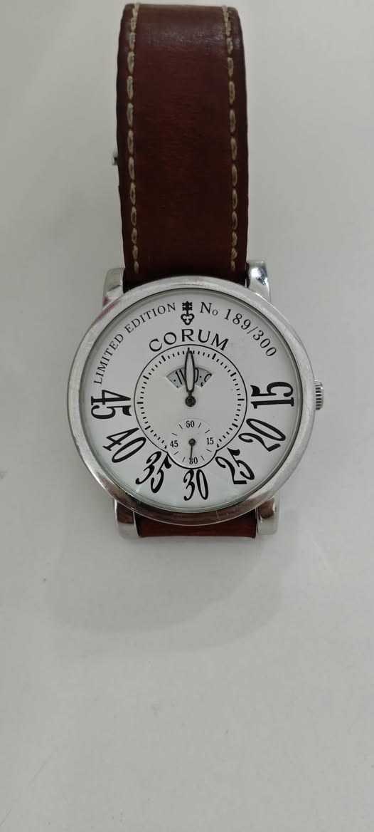 في الصورة هي ساعة Corum Classical Jump Hour (ساعة كوروم ذات الساعة القافزة)، وهي إصدار محدود (Limited Edition) يتميز بتصميم فريد لعرض الوقت.المميزات والمواصفات الفنيةنظام الساعة القافزة (Jump Hour): بدلاً من عقرب الساعات التقليدي، تظهر الساعة الحالية من خلال نافذة صغيرة (فتحة) عند موضع الساعة 12.عرض الدقائق والثواني: تحتوي على عقرب مركزي كبير للإشارة إلى الدقائق على مقياس "انفجاري" للأرقام العربية، بالإضافة إلى ميناء فرعي صغير للثواني عند موضع الساعة 6.الإصدار: هذا الموديل إصدار محدود للغاية، حيث تم إنتاج 300 قطعة فقط منه حول العالم (القطعة في الصورة تحمل رقم 189 من 300).الحجم والمادة: تأتي بهيكل من الفولاذ المقاوم للصدأ (Stainless Steel) بقطر يبلغ غالباً 42 ملم.المحركة: تعمل بحركة ميكانيكية (يدوية التعبئة في بعض الموديلات وأوتوماتيكية في أخرى).


**إذا كنت صاحب هذا الإعلان وتريد حذفه لأي سبب، رجاءا أرسل رسالة إلى الدعم الفني**