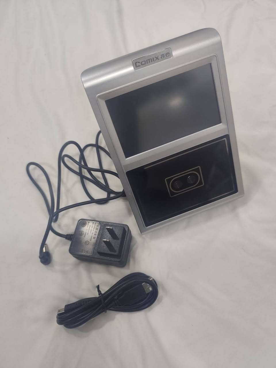 ا الجهاز هو جهاز بصمة الوجه (Face Recognition Terminal) من ماركة Comix، وهو مخصص لإدارة الحضور والانصراف للموظفين أو للتحكم في الدخول (Access Control).
إليك التفاصيل التقنية والوظائف بناءً على الصور المرفقة:
1. الوظائف الأساسية للجهاز
التعرف على الوجه: يستخدم الكاميرات المزدوجة والحساسات الضوئية (المصابيح الأرجوانية الظاهرة في الصور) للتعرف على ملامح الوجه بدقة، حتى في الإضاءة المنخفضة.
تسجيل الحضور والانصراف: يتيح للموظفين تسجيل وقت الدخول والخروج بمجرد الوقوف أمام الجهاز.
إدارة البيانات: يحتوي على قائمة "Report" لاستخراج تقارير الحضور مباشرة، وقائمة "Schedule" لضبط مواعيد العمل والنوبات.
2. المواصفات الظاهرة
الشاشة: شاشة ملونة تعمل باللمس لعرض القوائم والتعليمات.
المنافذ الجانبية:
USB: لسحب التقارير على "فلاش ميموري" أو تحديث النظام.
Mini USB: للاتصال المباشر بالكمبيوتر.
فتحة الطاقة: لتوصيل المحول الكهربائي (5 فولت غالباً).
زر Reset: لإعادة تشغيل الجهاز في حال حدوث تعليق.
3. شرح أيقونات القائمة الرئيسية
كما يظهر في الصورة الثالثة:
User: لإضافة موظف جديد، التقاط صورته، أو تعديل بياناته.
Schedule: لضبط ساعات العمل الرسمية والعطلات.
Report: لاستخراج جداول الحضور بصيغة Excel.
System: لضبط الوقت والتاريخ، اللغة، وإعدادات الشبكة.
Bell: لضبط تنبيهات صوتية (جرس) في أوقات معينة.
User Info: لعرض سجلات الموظفين المسجلين حالياً.


**إذا كنت صاحب هذا الإعلان وتريد حذفه لأي سبب، رجاءا أرسل رسالة إلى الدعم الفني**