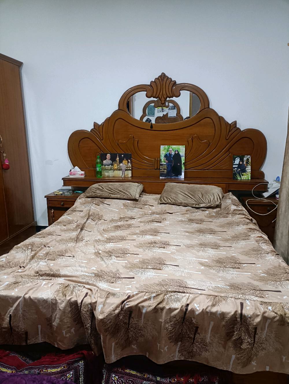 غرفة نوم خشبية بحالة جيدة تتكون من سرير مزدوج بألواح رأس مزخرفة، دولابات متعددة الاستخدام، وتسريحة بمرايا كبيرة. مناسبة لمن يبحث عن تصميم كلاسيكي وأداء وظيفي.