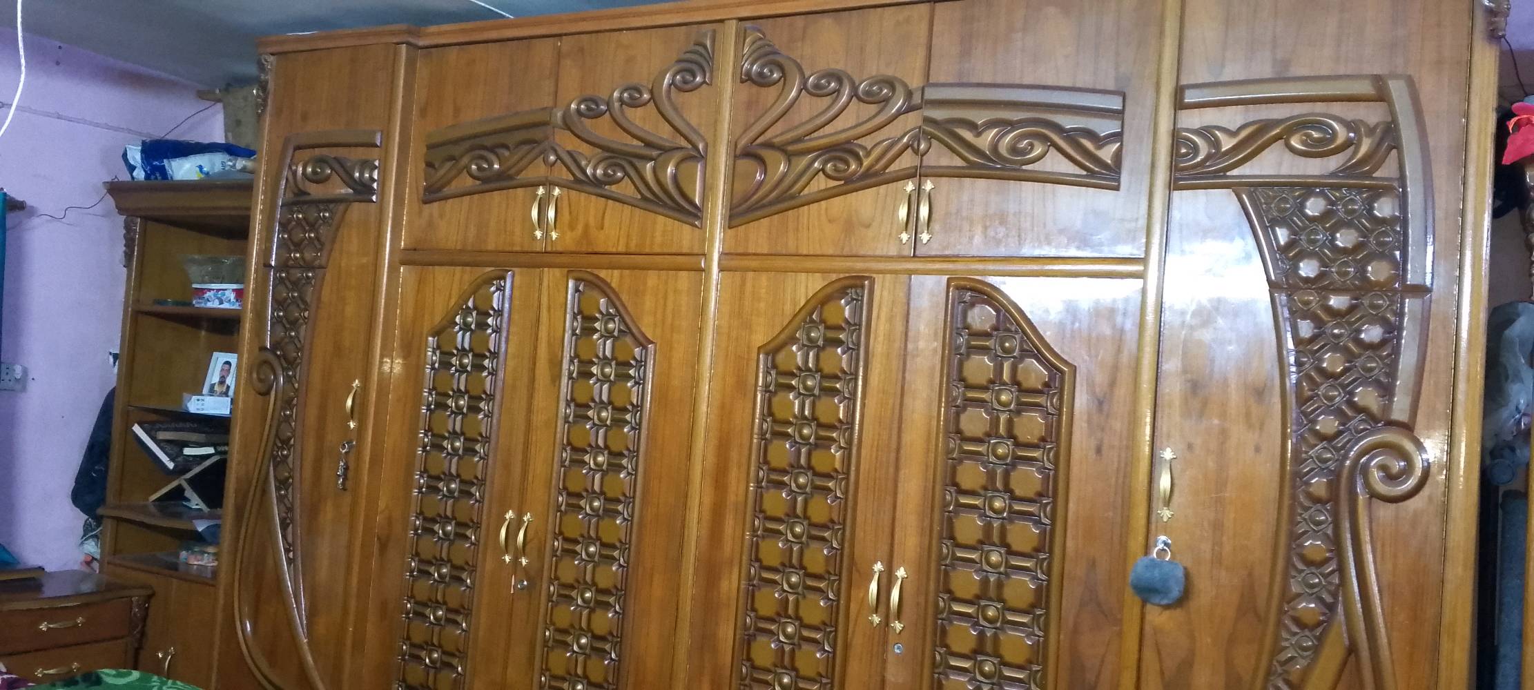 غرفة نوم راقية مصنوعة من الخشب المتين وتتميز بتصميم أنيق وزخارف جميلة. تحتوي على خزانة واسعة مع رفوف وأدراج مختلفة، بالإضافة إلى سرير مريح ومراية كبيرة مثبته على طاولة التسريح. الغرفة بحالة جيدة جداً وجاهزة للاستخدام الفوري.