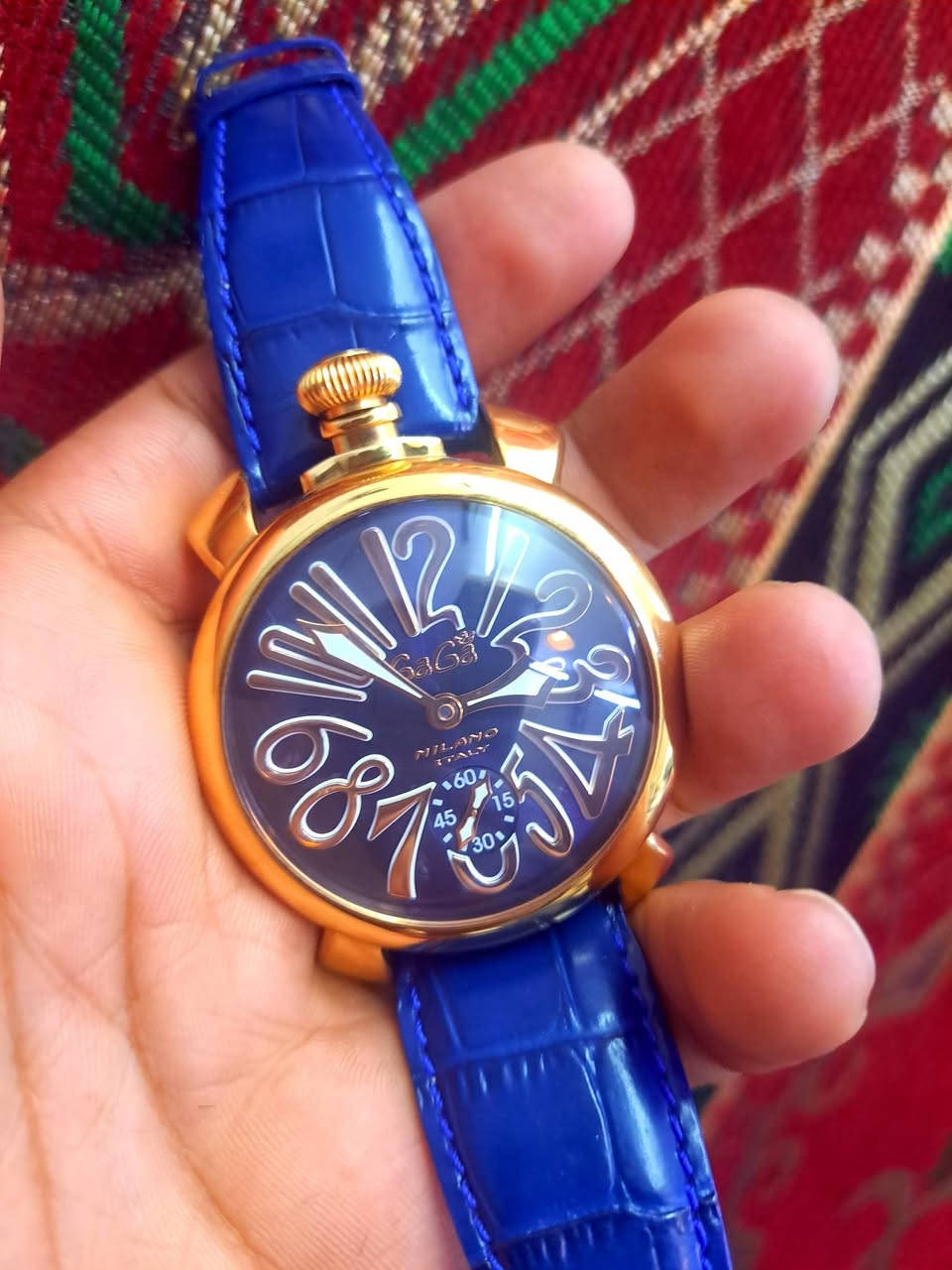 450 _$
الساعة المعروضة في الصورة هي من ماركة GaGà Milano، وتحديداً من مجموعة Manuale 48mm الشهيرة بتصميمها الإيطالي الجريء. 
 
تتميز هذه الساعة بالمواصفات التالية:
الموديل: Manuale 48mm، وغالباً ما تحمل الرقم المرجعي 5011 (مثل 5011.05S أو 5011MN05R0LABL0).
الحركة: ميكانيكية ذات تعبئة يدوية (Manual winding).
الهيكل: مطلي بالذهب الوردي (Rose gold plated) بقطر 48 ملم.
الميناء: ميناء باللون الأزرق الداكن مع أرقام عربية بارزة وكبيرة الحجم، وهي العلامة المميزة لتصاميم "غاغا ميلانو".
الحزام: جلد طبيعي باللون الأزرق بتصميم نقشة التمساح.
المميزات: تتضمن ميناء فرعياً صغيراً للثواني عند الساعة 6، وتاجاً كبيراً يقع عند الساعة 12 (تصميم يشبه ساعات الجيب القديمة).


**إذا كنت صاحب هذا الإعلان وتريد حذفه لأي سبب، رجاءا أرسل رسالة إلى الدعم الفني**