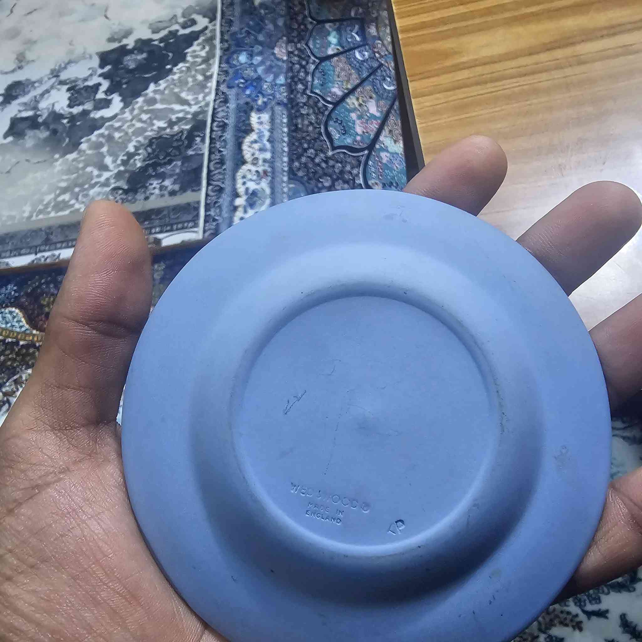 هذا الصحن هو قطعة فنية من فخار جاسبر وير (Jasperware) الشهير
من إنتاج شركة ويدجوود (Wedgwood) البريطانية العريقة.
​إليك التفاصيل حول هذه القطعة:
​ما هو هذا الشيء؟
​النوع: يُعرف بـ "جاسبر وير" باللون الأزرق الفاتح (Pale Blue Jasperware).
​التصميم: يتميز بالنقوش البيضاء البارزة المصنوعة من الكامي أو البورسلين، والتي عادة ما تصور مشاهد كلاسيكية أو أسطورية مستوحاة من الفن اليوناني والروماني القديم.
​الاستخدام: يُستخدم كقطعة ديكور أو صحن صغير للزينة (Trinket Dish).
​إلى أي سنة يعود؟
​بناءً على الختم الموجود في خلفية الصحن (WEDGWOOD - MADE IN ENGLAND):
​الفترة الزمنية: كلمة "MADE IN ENGLAND" بدأت الشركة باستخدامها بعد عام ١٩٠٨ 

 قطعة أصلية من إنتاج المصنع في إنجلترا وليس تقليداً


**إذا كنت صاحب هذا الإعلان وتريد حذفه لأي سبب، رجاءا أرسل رسالة إلى الدعم الفني**