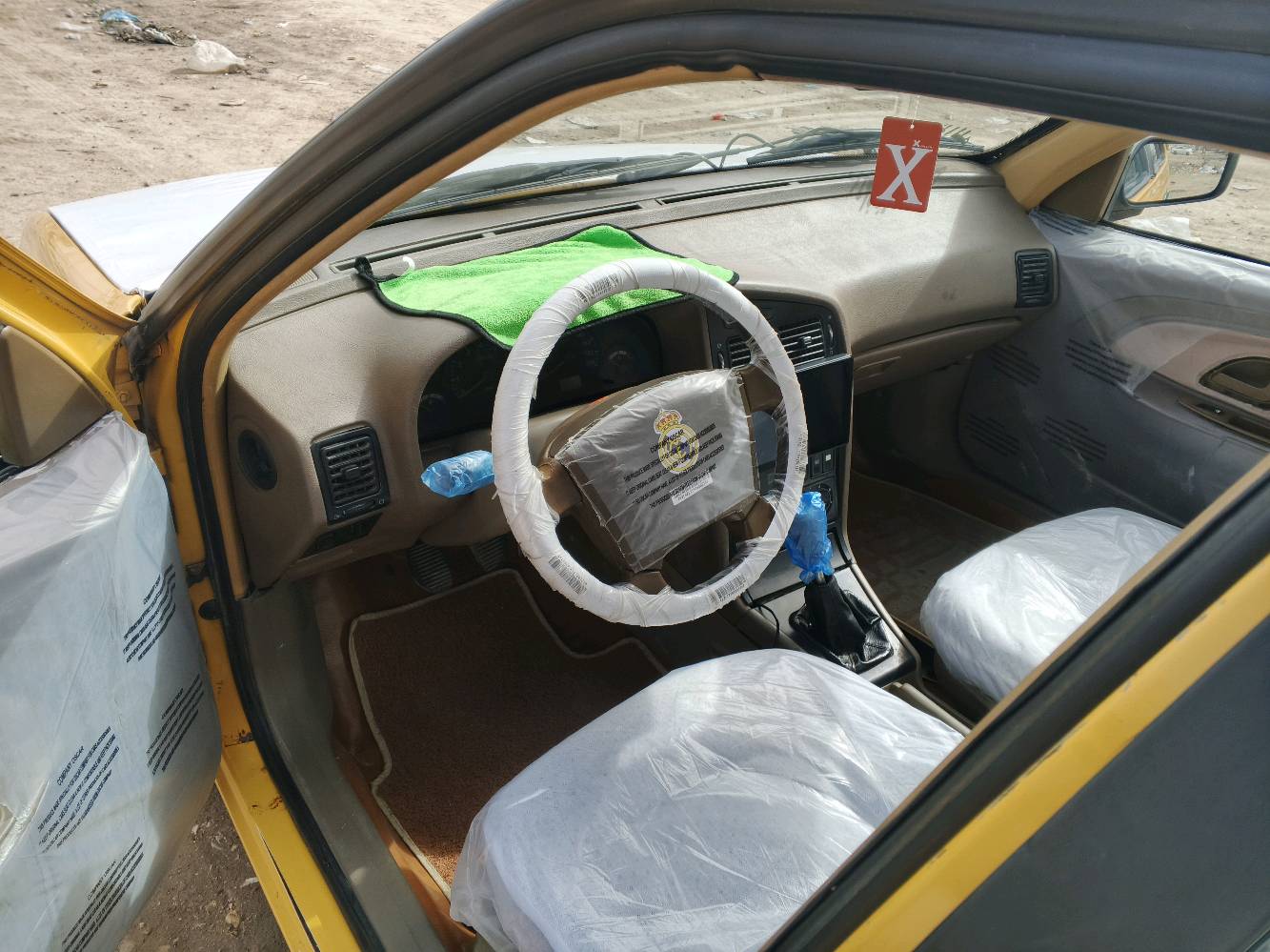 السيارة المعروضة للبيع هي بيجو بلون أصفر مع إكسسوارات زرقاء وسقف أبيض مميز. المقاعد مُغطاة بواقٍ بلاستيكي للحفاظ على النظافة، والمقود مُغطى بتغليف لضمان حماية إضافية. السيارة تبدو في حالة جيدة ولا توجد أضرار ظاهرة في الهيكل الخارجي أو الداخلي. الصندوق الخلفي واسع وكافٍ لحمل الأغراض. هذه السيارة مثالية للاستخدام اليومي أو للأعمال بفضل حالتها المحافظة والتجهيزات الأساسية المتوفرة فيها.