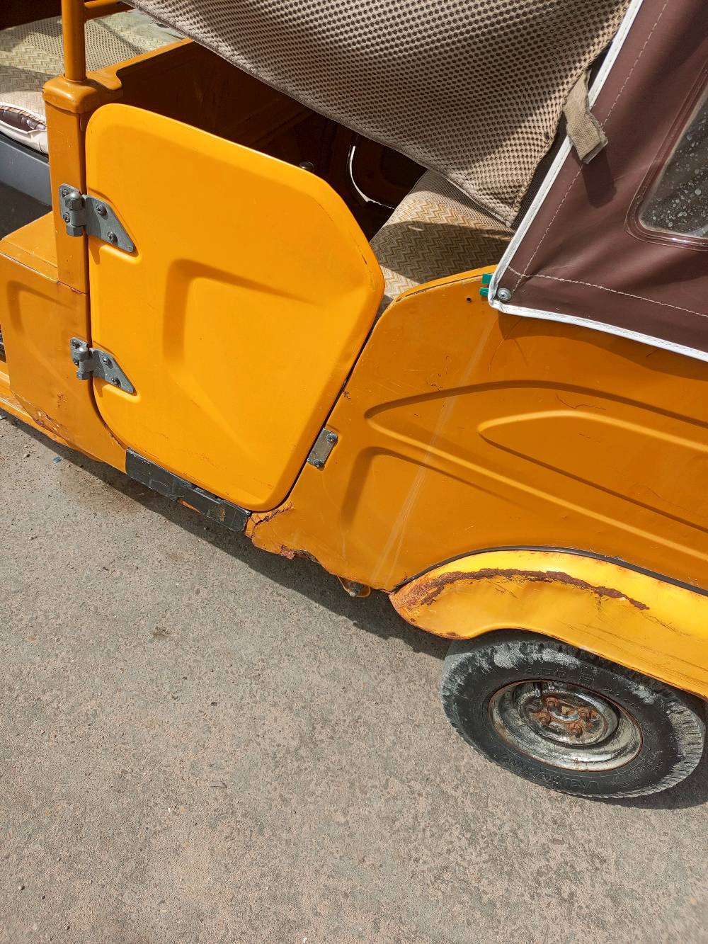 هذا التكتك متين ولونه برتقالي، مثالي للتنقل داخل المدينة وتحمل الأحمال الخفيفة. تصميمه عملي جداً ويشمل سقفًا للحماية من الشمس والمطر. هيكله يحتاج لبعض الإصلاحات السطحية ولكن التحكم به سهل ومريح. مناسب للاستخدام الشخصي أو كوسيلة نقل.