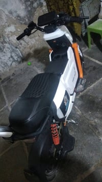 دراجة كهربائية بحالة جيدة، لونها أبيض مع تفاصيل برتقالية. التصميم عصري...