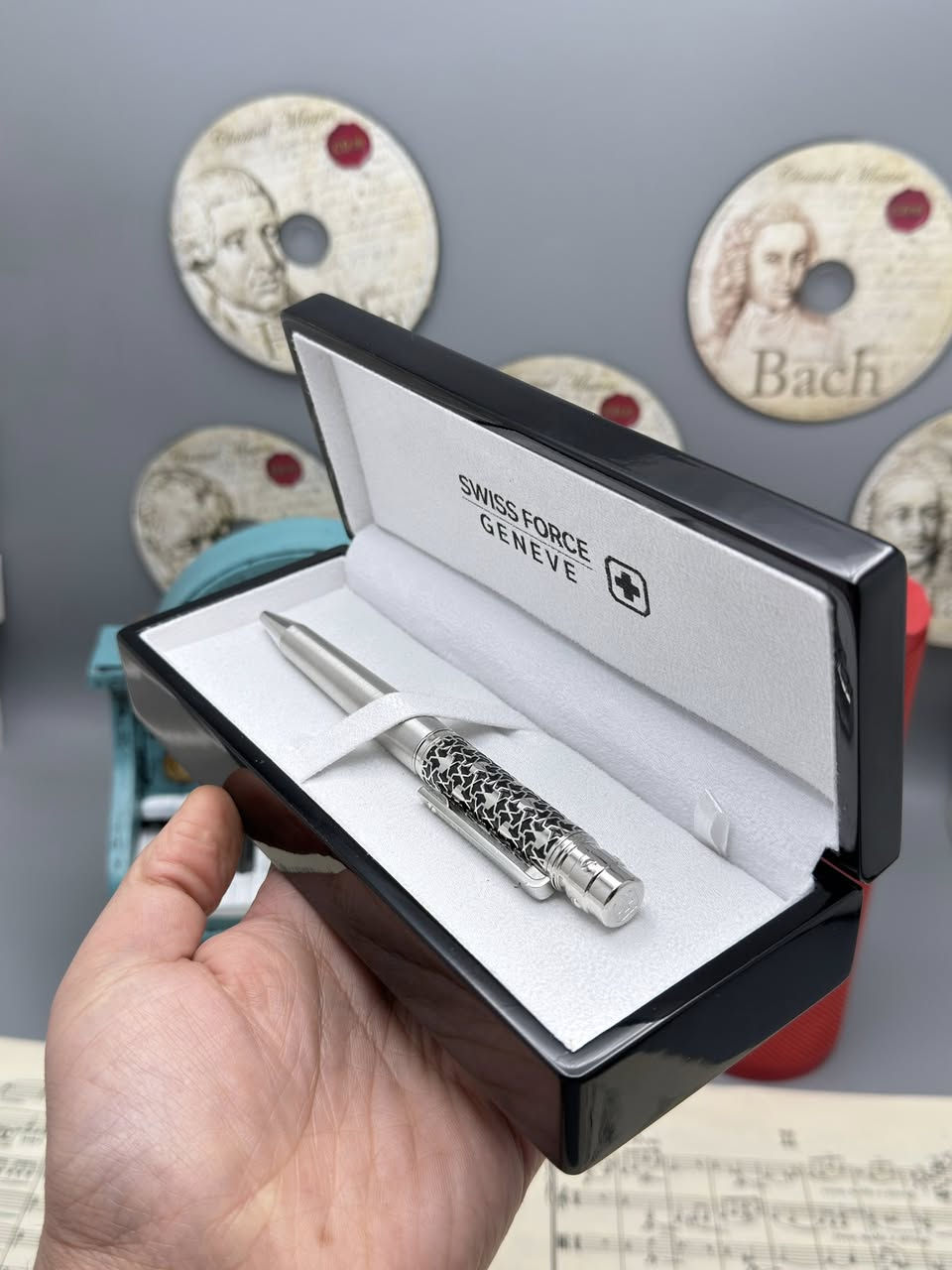 نينا ريتشي (Nina Ricci). هذه الأقلام تُعرف بكونها إكسسوارات فاخرة تجمع بين الأناقة الباريسية والعملية.
إليك شرح مفصل لما تظهره الصور:
1. العلامة التجارية والجودة
• الماركة: Nina Ricci هي دار أزياء راقية، وأقلامها تُصنف كأدوات كتابة "برستيج" (Prestige).
• الأصالة: يظهر في الصور "شهادة أصالة" (Certificate of Authenticity)، مما يؤكد أن القلم أصلي ويأتي مع ضمان (غالباً لمدة سنتين ضد عيوب التصنيع).
2. التصاميم والموديلات الظاهرة
من خلال الصور، نرى أربعة أشكال مختلفة، مما يوفر خيارات متنوعة للأذواق:
• القلم الأول (بني مموج): يتميز بنقشة "Tortoise" أو التورتويز (صدفة السلحفاة) الكلاسيكية مع لمسات معدنية داكنة. هذا التصميم يوحي بالفخامة التقليدية والمظهر الدافئ.
• القلم الثاني (أسود وفضي): تصميم كلاسيكي "مينيماليست" باللون الأسود اللامع مع حواف فضية، وهو مثالي لرجال الأعمال والمناسبات الرسمية.
• القلم الثالث (ذهبي مخطط): قلم باللون الذهبي الكامل مع خطوط طولية محفورة، يعطي طابعاً ملكياً لافتاً للنظر.
• القلم الرابع (فضي/كروم مخطط): مشابه للذهبي ولكن باللون الفضي، يتميز بالهدوء والعصرية، ومقاوم بشكل جيد للخدوش بفضل المادة المعدنية.
3. المواصفات الفنية
• نوع القلم: يظهر من الرؤوس أنها أقلام حبر جاف (Ballpoint) تعمل غالباً بآلية التدوير (Twist mechanism) لفتح وإغلاق القلم.
• الخامات: الهيكل عادة ما يكون مصنوعاً من النحاس المطلي بالروديوم، الذهب، أو الورنيش عالي الجودة (Lacquer).
• التغليف: يأتي في علبة بيضاء فاخرة مبطنة من الداخل بكلمة "NINA RICCI" مطبوعة بشكل أنيق، مما يجعله خياراً ممتازاً للهدايا.
4. مميزات الاقتناء
• الوزن: هذه الأقلام تمتاز بوزن متزن (ليست خفيفة جداً ولا ثقيلة)، مما يوفر راحة أثناء الكتابة الطويلة.
• سهولة التعبئة: تستخدم عبوات حبر قياسية متوفرة بسهولة في المكتبات الكبرى.
• القيمة: يعتبر قطعة إكسسوار تكمل المظهر الشخصي، تماماً مثل الساعة أو المحفظة.

للحجز والاستفسار 
***********
