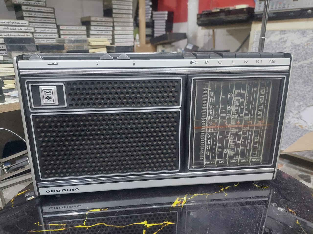 ما شاء الله، هذه القطعة تعتبر تحفة فنية لهواة الانتيك والأجهزة الألمانية الرصينة. هذا الراديو من نوع جروندينج (Grundig)، وهي ماركة غنية عن التعريف بجودة التقاط الإشارة ونقاء الصوت.
​إليك مقترح لإعلان بيع جذاب ومحترف يناسب قيمة هذا الجهاز:
​📻 للبيع: راديو GRUNDIG ألماني أصلي - تحفة كلاسيكية
​لعشاق الزمن الجميل وأصحاب الذوق الرفيع، معروض للبيع راديو جروندينج (Grundig) بتصميمه الكلاسيكي الفخم، يجمع بين الأداء القوي والمظهر التراثي الأنيق.
​✨ مميزات الجهاز:
• ​الصناعة: جودة ألمانية أصلية معروفة بمتانتها.
• ​الموجات: يدعم نطاق واسع من الموجات (FM, LW, MW, SW1, SW2) لالتقاط المحطات المحلية والعالمية.
• ​الحالة: الجهاز بحالة ممتازة (كما هو موضح بالصور)، مع الحفاظ على الهيكل الخارجي والشبك الأمامي.
• ​الصوت: يتميز بنقاء صوت جروندينج الشهير مع وجود مفاتيح للتحكم في النغمات (Bass & Treble).
• ​التصميم: واجهة كلاسيكية مع مؤشرات تردد واضحة وإضاءة خلفية تضفي لمسة جمالية في المساء.
​📐 تفاصيل إضافية:
• ​هوائي (Antenna) طويل وقابل للسحب لضمان أفضل إشارة.
• ​يعمل بكفاءة عالية ويعتبر قطعة ديكور مثالية للمكاتب أو المجالس التراثية.
​💰(السعر على الخاص البسيط للصادقين)
📍 الموقع: [كربلاء]
📞 للتواصل: [***********]
