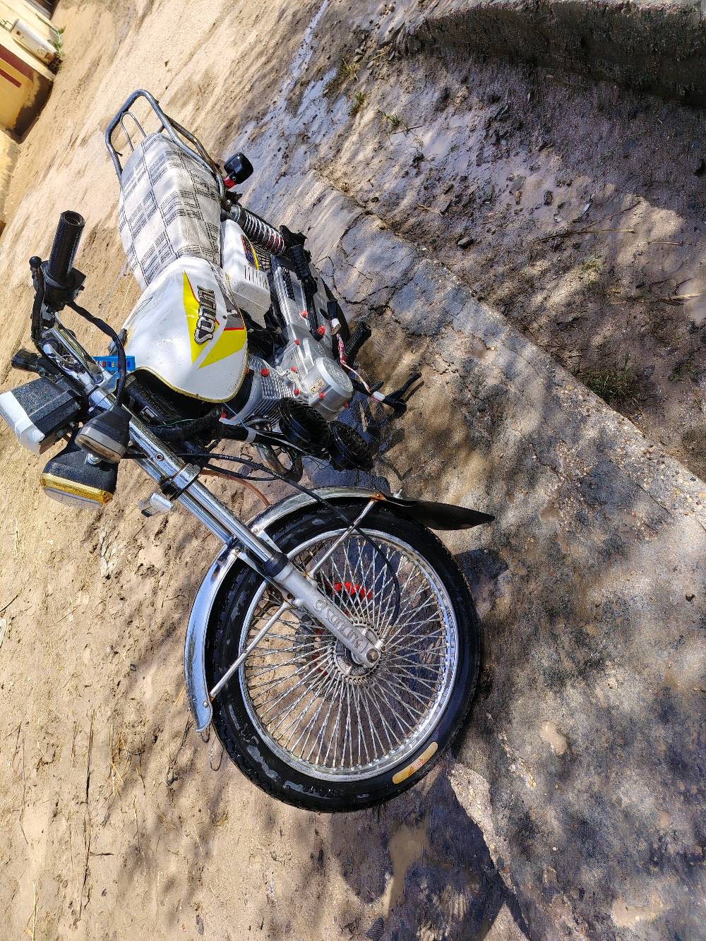 دراجة نارية نوع دايون CG125 بحالة ممتازة، لونها أبيض مع رسومات جانبية. الدراجة نظيفة ومجهزة بالكامل، مما يجعلها مثالية للاستخدام اليومي أو المشاوير الطويلة.