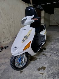 دراجة نارية نوع سكوتر لون أبيض مع زخارف أنيقة. مناسبة للتنقل في المدين...