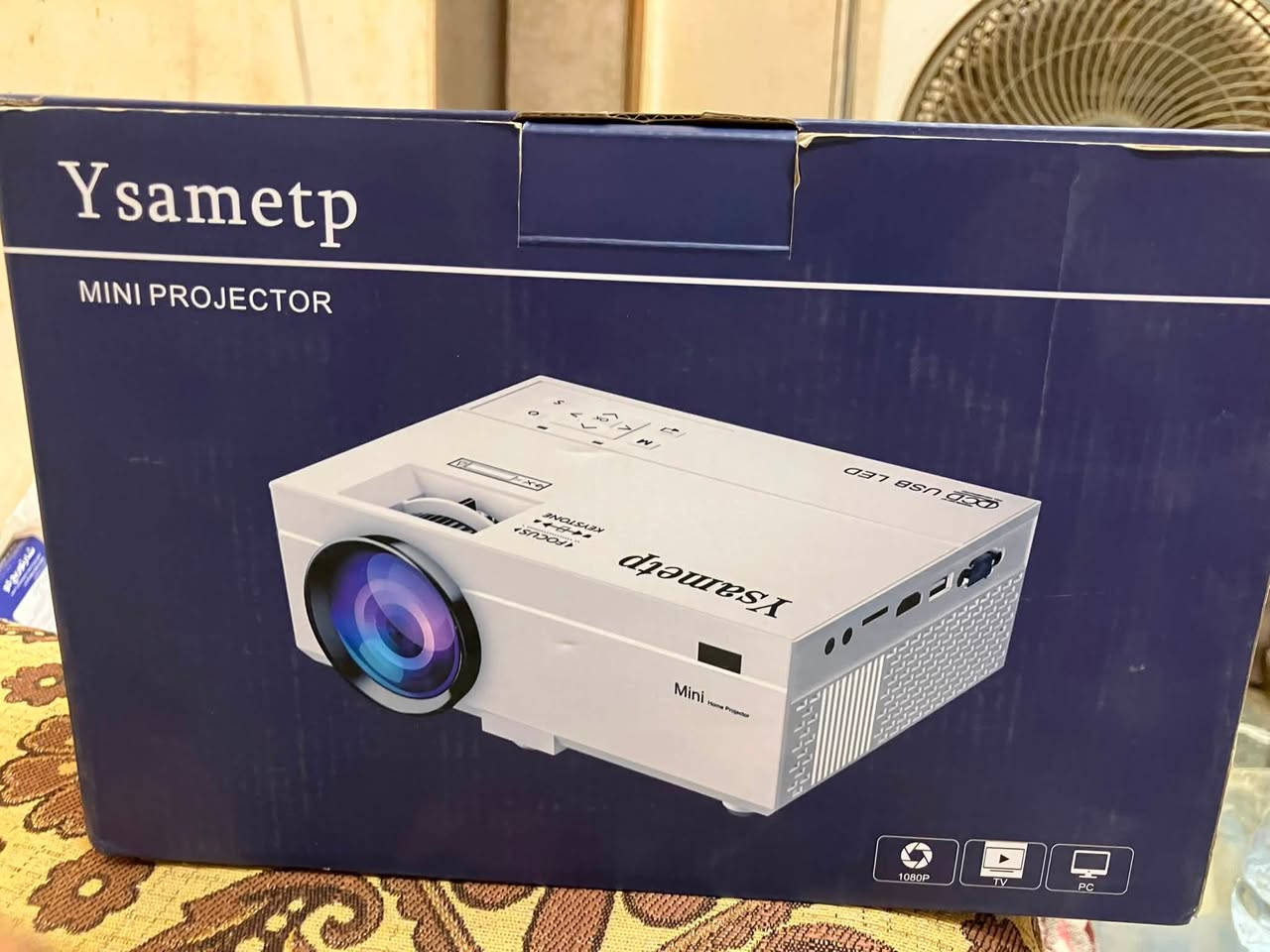 السعر ٨ الاف جديد 
إن جهاز العرض الصغير Ysametp Mini Projector هو بروجيكتور محمول واقتصادي، ومصمم خصيصاً لإنشاء تجربة سينما منزلية مدمجة وسهلة التنقل. يشتهر الجهاز بدعمه لدقة العرض العالية وخيارات التوصيل المتنوعة التي تجعله خياراً ممتازاً لمشاهدة الأفلام والألعاب.إليك التفاصيل الكاملة والمواصفات والمميزات الخاصة بجهاز Ysametp:المواصفات التقنية الأساسيةدقة العرض: يدعم دقة Full HD 1080P لتقديم صورة واضحة ومفصلة.نسبة التباين: تصل إلى 10000:1 مما يمنح الألوان عمقاً ووضوحاً أفضل.حجم الشاشة: يقدم تجربة عرض مرنة تتراوح من 50 بوصة إلى 200 بوصة بحسب مسافة الإسقاط.مسافة العرض الموصى بها: يفضل وضعه على مسافة تتراوح بين 1.5 إلى 5 أمتار من الحائط أو الشاشة.عمر اللمبة (LED): يدوم لفترة طويلة جداً تصل إلى 55,000 ساعة تشغيل.المنافذ والاتصاليأتي البروجيكتور مزوداً بمجموعة شاملة من المنافذ لتوصيل كافة أجهزتك الذكية:HDMI: لتوصيل أجهزة الكمبيوتر، اللاب توب، منصات الألعاب (مثل PS4/PS5)، وأجهزة التلفاز الذكية (TV Stick).USB & TF Card: لتشغيل ملفات الفيديو والصور مباشرة من الفلاش ميموري أو كروت الذاكرة.AV & VGA: للتوافق مع الأجهزة القديمة.مخرج صوت 3.5mm: لتوصيل سماعات الرأس أو مكبرات الصوت الخارجية.أبرز المميزاتتصميم صغير وخفيف: يزن حوالي 1 كجم تقريباً (2.15 رطل) وأبعاده المدمجة تجعل من السهل وضعه في حقيبة الظهر للتنقل به.صوت ستيريو مدمج: يحتوي على مكبرات صوت ستيريو ثنائية مدمجة توفر صوتاً سينمائياً محيطياً دون الحاجة لسماعات خارجية في الغرف الصغيرة.حماية العين ونظام تبريد هادئ: يعتمد على نظام إضاءة LED مريح للعين لتقليل الإجهاد أثناء المشاهدة الطويلة، مع مروحة تبريد متطورة تعمل بصوت منخفض جداً.الاتصال بالهواتف الذكية: تتوفر منه طرازات تدعم الاتصال اللاسلكي (Wi-Fi) لعرض شاشة هواتف آيفون وأندرويد مباشرة، بينما تتطلب الطرازات الأساسية استخدام وصلة تحويل من الهاتف إلى منفذ HDMI.محتويات العلبة النموذجيةعند الشراء، تأتي العبوة غالباً محملة بالملحقات التالية لتبدأ التشغيل فوراً:جهاز العرض الصغير Ysametp.حامل ثلاثي القوائم (Tripod) لتثبيت الجهاز وتوجيهه.جهاز تحكم عن بعد (Remote Control).كابل HDMI وكابل الطاقة وكابل AV المعياري.حقيبة قماشية برباط لتسهيل الحمل والحماية.


**إذا كنت صاحب هذا الإعلان وتريد حذفه لأي سبب، رجاءا أرسل رسالة إلى الدعم الفني**