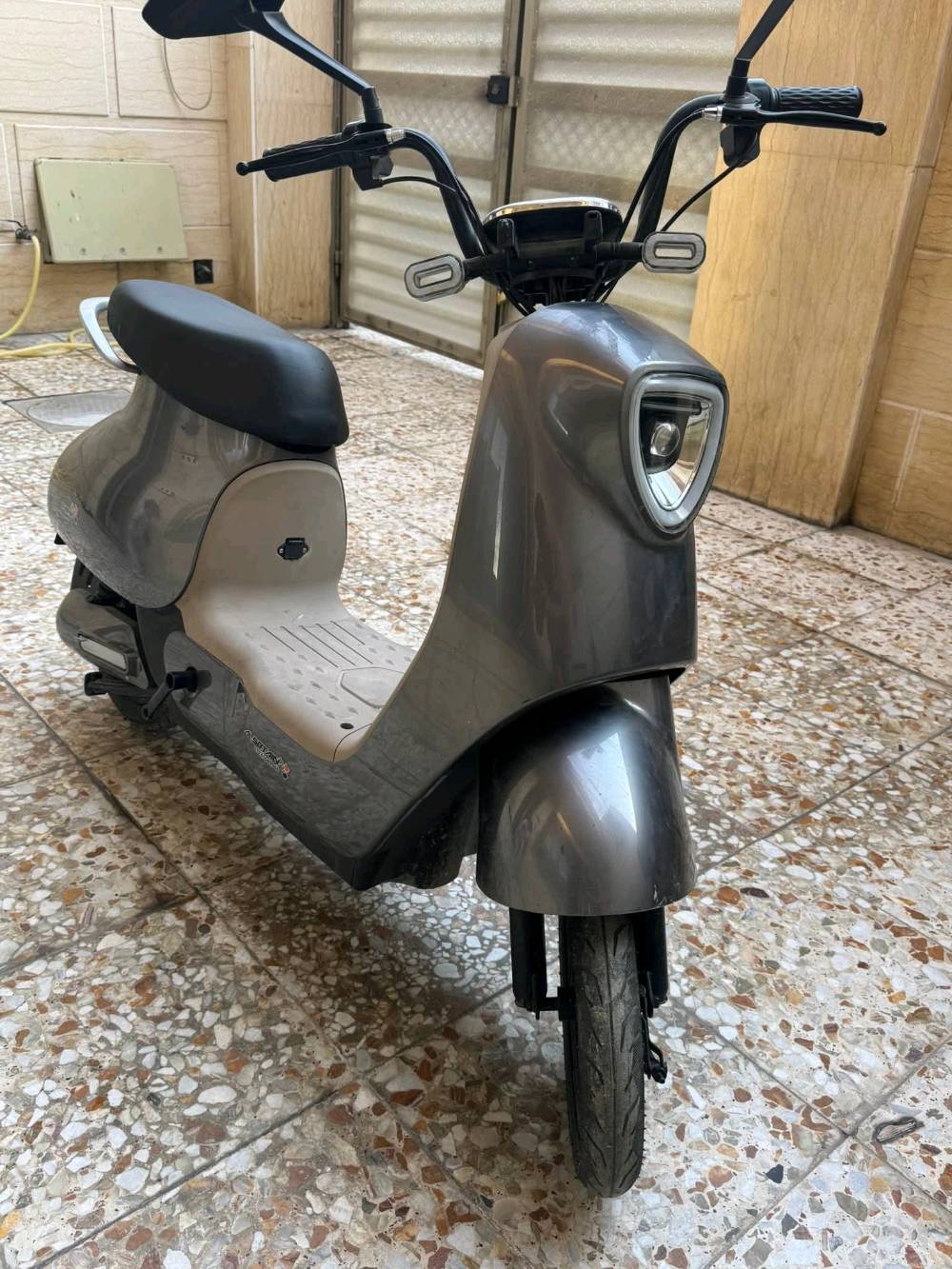 دراجة كهربائية أنيقة باللون الرمادي، مثالية للتنقل السريع والسهل داخل المدينة. تتميز بتصميم مريح وعصري مع مصابيح أمامية قوية لزيادة الأمان أثناء القيادة في الليل. تم استخدام الدراجة بحالة ممتازة وتعمل بكفاءة عالية.