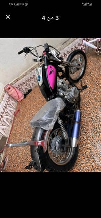 دراجة نارية بحالة جيدة مع تصميم أنيق يجمع بين اللون الأسود والوردي، مر...