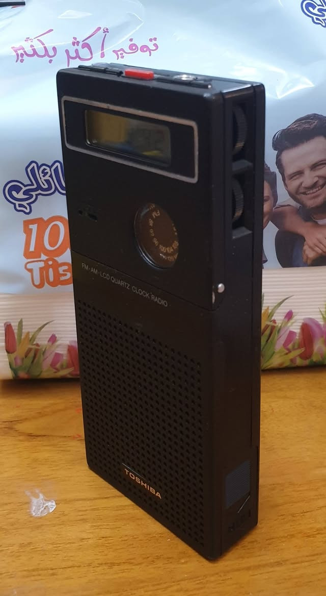 هذا الجهاز هو راديو ترانزستور وساعة منبه محمولة كلاسيكية من إنتاج شركة توشيبا (Toshiba)، ويُعرف بالتحديد بموديل Toshiba RC-1790.
قبل لا تقرأ وتعب نفسك السعر 165
.....       .......     ......      .....
فيما يلي المواصفات والميزات الرئيسية لهذا الجهاز بناءً على تصميمه:

الوظيفة الأساسية: يعمل كجهاز راديو (AM/FM) وساعة رقمية مع منبه. [1]

نطاقات الراديو: يدعم موجات FM (بين 88-108 ميجاهرتز) وموجات AM (بين 540-1600 كيلوهرتز)، ويتم التحكم في التردد عبر قرص دائري في واجهة الجهاز.

الشاشة: شاشة LCD رقمية تعرض الوقت بوضوح، مع مفتاح جانبي للتبديل بين أوضاع التشغيل (إيقاف، تشغيل، تشغيل تلقائي "AUTO" للمنبه، والمنبه "ALARM").

الهوائي: مزود بهوائي معدني تلسكوبي قابل للسحب لتحسين استقبال إشارة الراديو. [1]

التصميم: يتميز بحجم صغير مناسب للجيب أو السفر، ويأتي عادة مع حافظة جلدية سوداء (كما يظهر في الصورة) لحمايته.

سنة الصنع: هذا الموديل يعود لفترة الثمانينيات (حوالي عام 1981) وصُنع في اليابان.

هذا الجهاز هو راديو ترانزستور وساعة منبه محمولة كلاسيكية من إنتاج شركة توشيبا (Toshiba)، ويُعرف بالتحديد بموديل Toshiba RC-1790.


**إذا كنت صاحب هذا الإعلان وتريد حذفه لأي سبب، رجاءا أرسل رسالة إلى الدعم الفني**