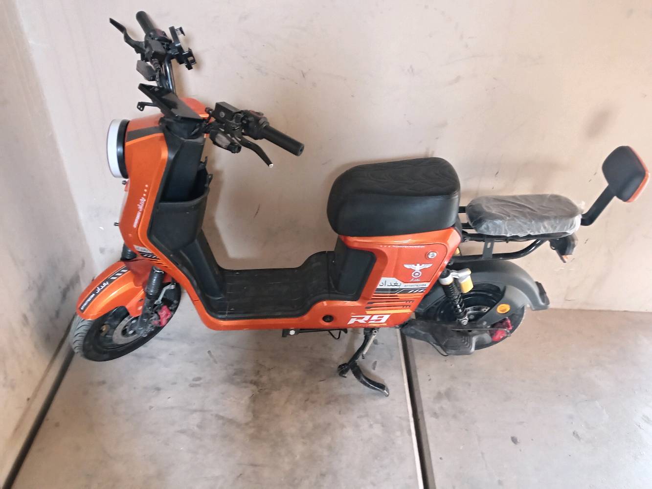 درّاجة كهربائية برتقالية اللون بحالة ممتازة. مناسبة للتنقل داخل المدينة. اقتصادية وسهلة الاستعمال، مثالية للجولات القصيرة.