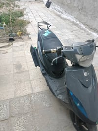 دراجة نارية نوع سكوتر بحالة جيدة، اللون رمادي مع شعار مميز على المقعد....