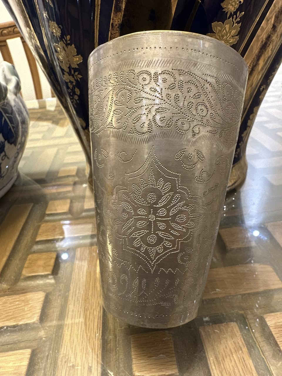 القطعة هي كوب "لاسي" (Lassi Cup) تقليدي، وهو نوع من الأكواب المنتشرة في جنوب آسيا والشرق الأوسط، وتُستخدم عادةً لتقديم المشروبات التقليدية أو كقطع ديكور
 القطعة مصنوعة من النحاس الأصفر (Brass) أو مزيج من القصدير والفضة الألمانية (German Silver)، وغالباً ما تكون مطلية بطبقة فضية لإعطائها هذا المظهر اللامع.
الزخرفة: تتميز بنقوش يدوية دقيقة (Hand Etched) تعتمد على تقنية التنقيط والخطوط المحفورة. الزخارف نباتية وهندسية تتسم بطابع تراثي شرقي أو فارسي.

السعر ٦٠,٠٠٠ دينار 
للاستفسار ***********
