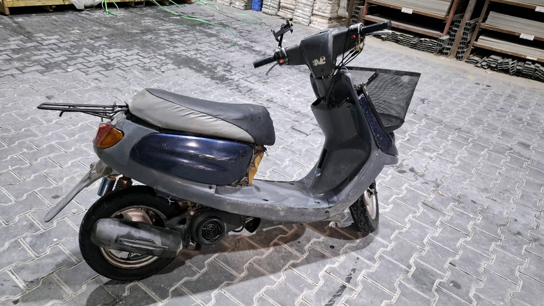 دراجة نارية سكوتر مستخدمة، لونها أزرق وغامقة، مناسبة للتنقلات اليومية داخل المدينة. تحتاج إلى بعض الصيانة في الجزء الأمامي ولكن بشكل عام حالة جيدة.

**الموقع:** بغداد