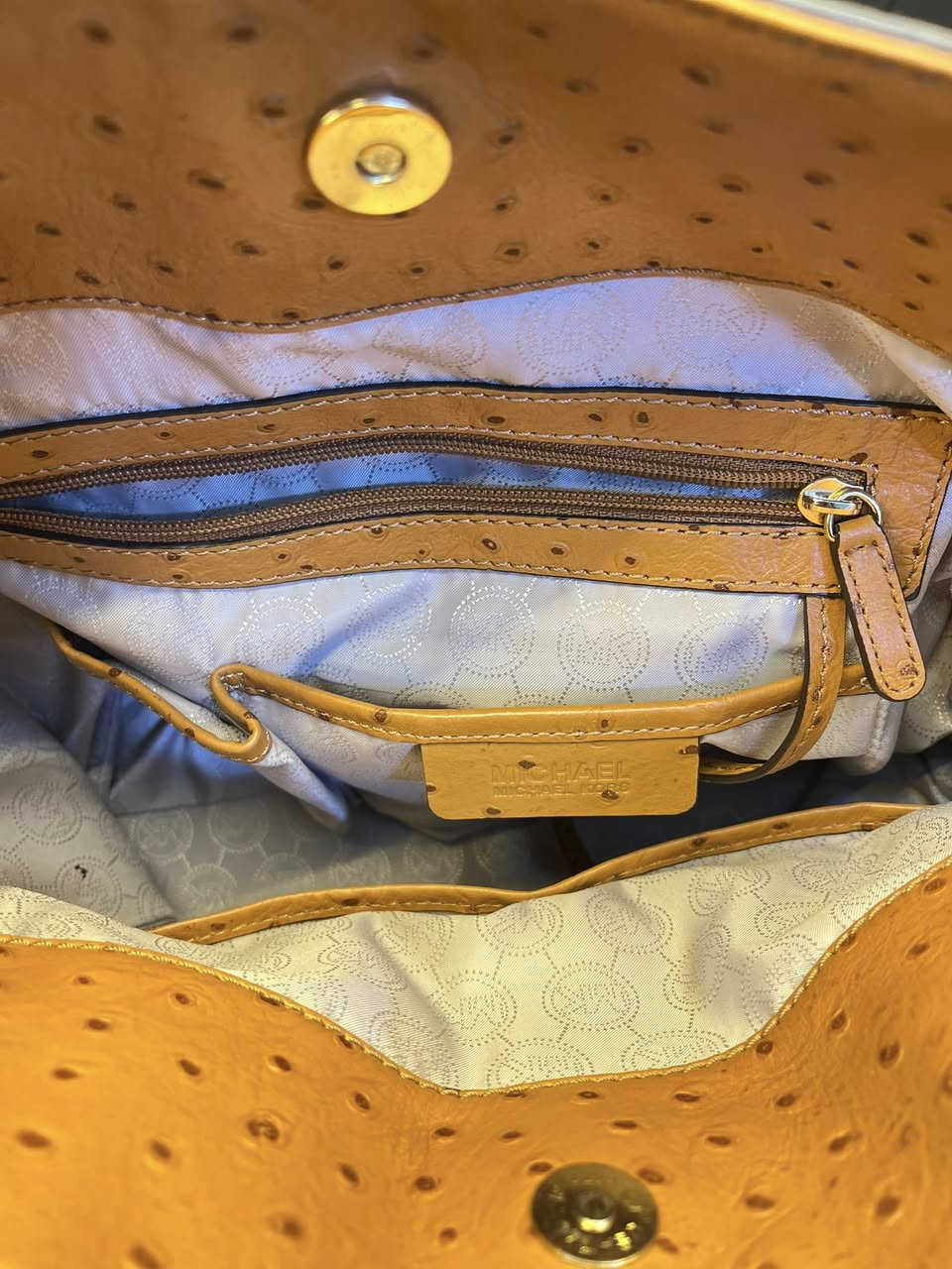 حقيبة اليد هذه هي حقيبة يد (توت) هاميلتون من مايكل كورس بنقشة النعام البارزة. تتميز الحقيبة بلونها البرتقالي المائل للسمرة وتفاصيلها الذهبية، بما في ذلك القفل المتدلي وحزام السلسلة الاختياري. 

العلامة التجارية: مايكل كورس (Michael Kors)
الموديل: هاميلتون (Hamilton)
الخامة: جلد بنقشة النعام البارزة
اللون: برتقالي أو تان (Orange/Tan)
الميزات: قفل ذهبي مميز، ومقابض علوية، وحزام كتف سلسلة اختياري
الحالة: مستخدمة استعمال خفيف – نظيفة وبحالة جيدة
• المناسبة: يومي، دوام، مناسبات خفيفة، سفر
• السعة: متوسطة – تشيل أغراض أساسية (محفظة، موبايل، مفاتيح، عطر)
للتواصل خاص : *********** فقط واتساب
