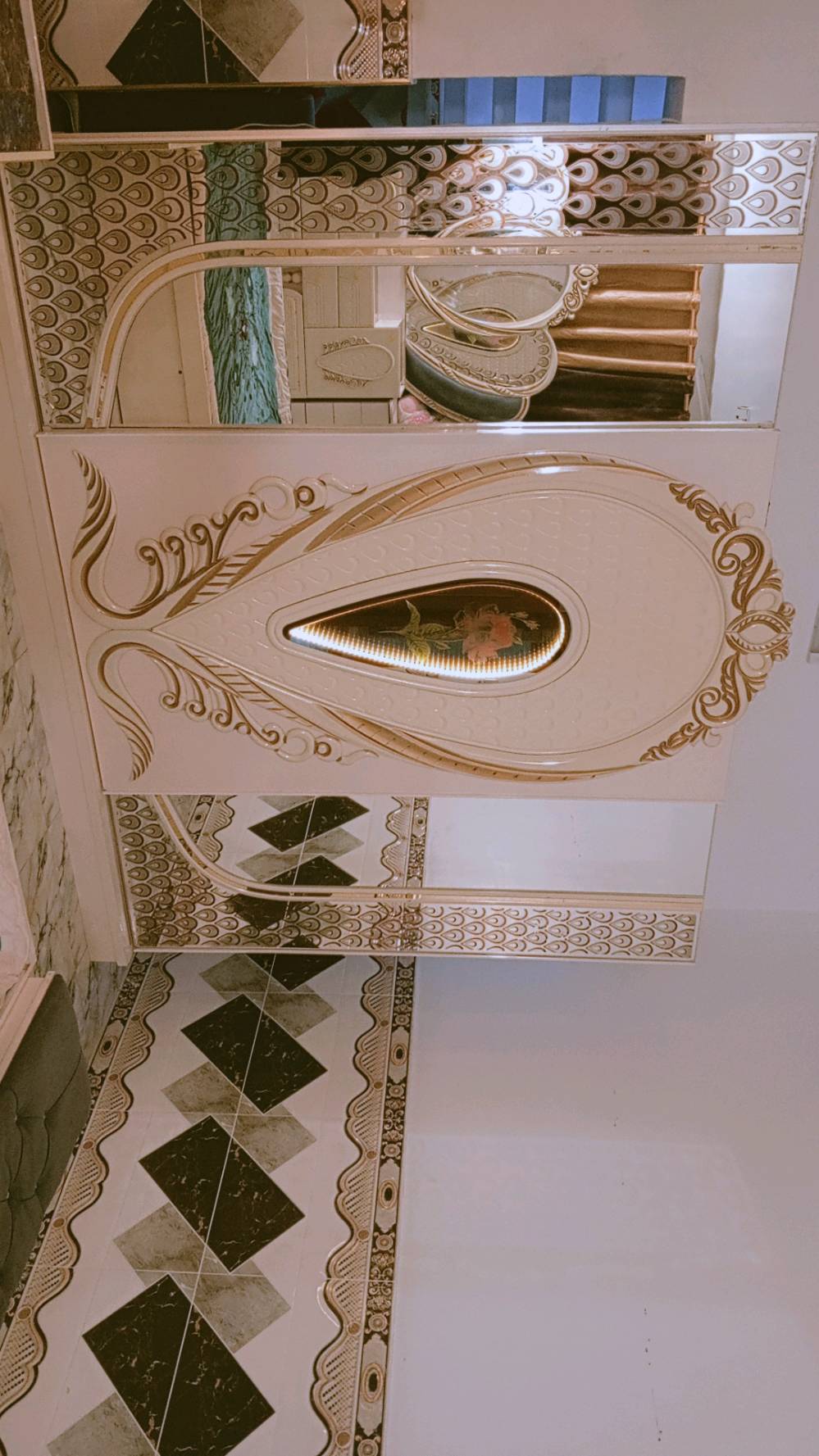 غرفة نوم مميزة بتصميم كلاسيكي فاخر، تتكون من سرير كبير ومريح مع لوح رأس ذو زخارف أنيقة ومرآة رائعة. الطقم يشمل أيضًا خزائن جانبية وتصميم فني على الجدران والخزائن. القطع مصنوعة بعناية لتضيف لمسة من الفخامة لأي غرفة نوم.