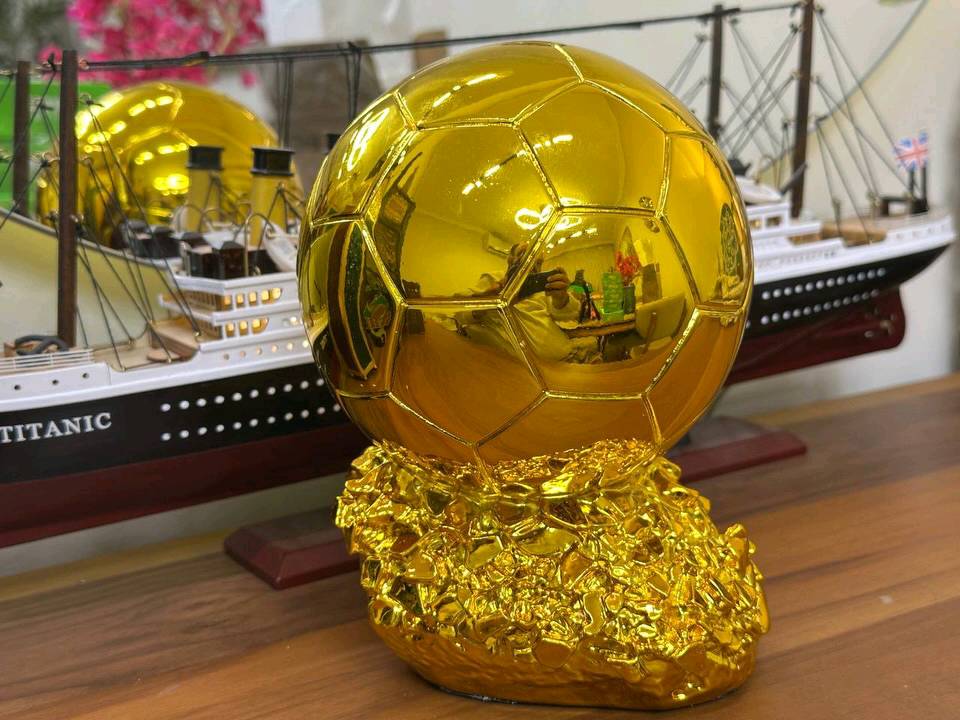 مجسم الكرة الذهبية (Ballon d'Or) الفاخر 
​عش شغف كرة القدم واقتنِ رمز التفوق الأسطوري! نقدم لكم مجسم "الكرة الذهبية" بتصميمه المذهل وتفاصيله الدقيقة، ليكون القطعة الأبرز في غرفتك، مكتبك، أو الهدية المثالية لعشاق الساحرة المستديرة. هذا المجسم ليس مجرد زينة، بل هو تحفة فنية تعكس روح الانتصار والبطولة.
​ أبرز مميزات المجسم:
​وزن ثقيل واحترافي: يتميز المجسم بـ وزن ثقيل يمنحه طابعاً احترافياً وقيمة عالية عند حمله، مما يجعله يحاكي شعور حمل الجوائز الحقيقية الفاخرة.
​طلاء ذهبي شديد اللمعان: يتمتع بلمسة ذهبية براقة وعاكسة للضوء بجودة استثنائية (كما يظهر بوضوح في الصور)، مما يضفي عليه مظهراً خاطفاً للأنظار.
​دقة في التفاصيل: تصميم الكرة يحمل تقطيعات سداسية مطابقة للواقع، مع نقش بارز وواضح لشعار "BALLON D'OR" على الواجهة.
​قاعدة فنية متينة: يستند المجسم على قاعدة صلبة ذات ملمس صخري ذهبي فريد، تزيد من ثباته وتضيف لمسة جمالية مضاعفة.
​لوحة إهداء مخصصة: تحتوي القاعدة على مساحة مستطيلة ناعمة وفارغة، وهي مثالية لحفر اسمك، اسم فريقك، أو كتابة إهداء خاص لشخص عزيز.
​الاستخدامات المثالية:
​هدية استثنائية: الخيار الأول والأفخم لأي شخص مهووس بكرة القدم (سواء كان لاعباً أو مشجعاً).
​ديكور فخم: يضيف طابعاً رياضياً أنيقاً عند وضعه على أرفف العرض، المكاتب، أو بجانب مقتنياتك الثمينة.
​جوائز البطولات: قطعة التتويج المثالية للبطولات المحلية، الدوريات الرمضانية، أو مسابقات البلايستيشن بين الأصدقاء.
السعر المذهل:
​احصل على هذه التحفة الفنية بسعر تنافسي جداً:
18,000 فقط!
​اطلبها الآن وتوج نفسك أو من تحب بأعرق جوائز كرة القدم!