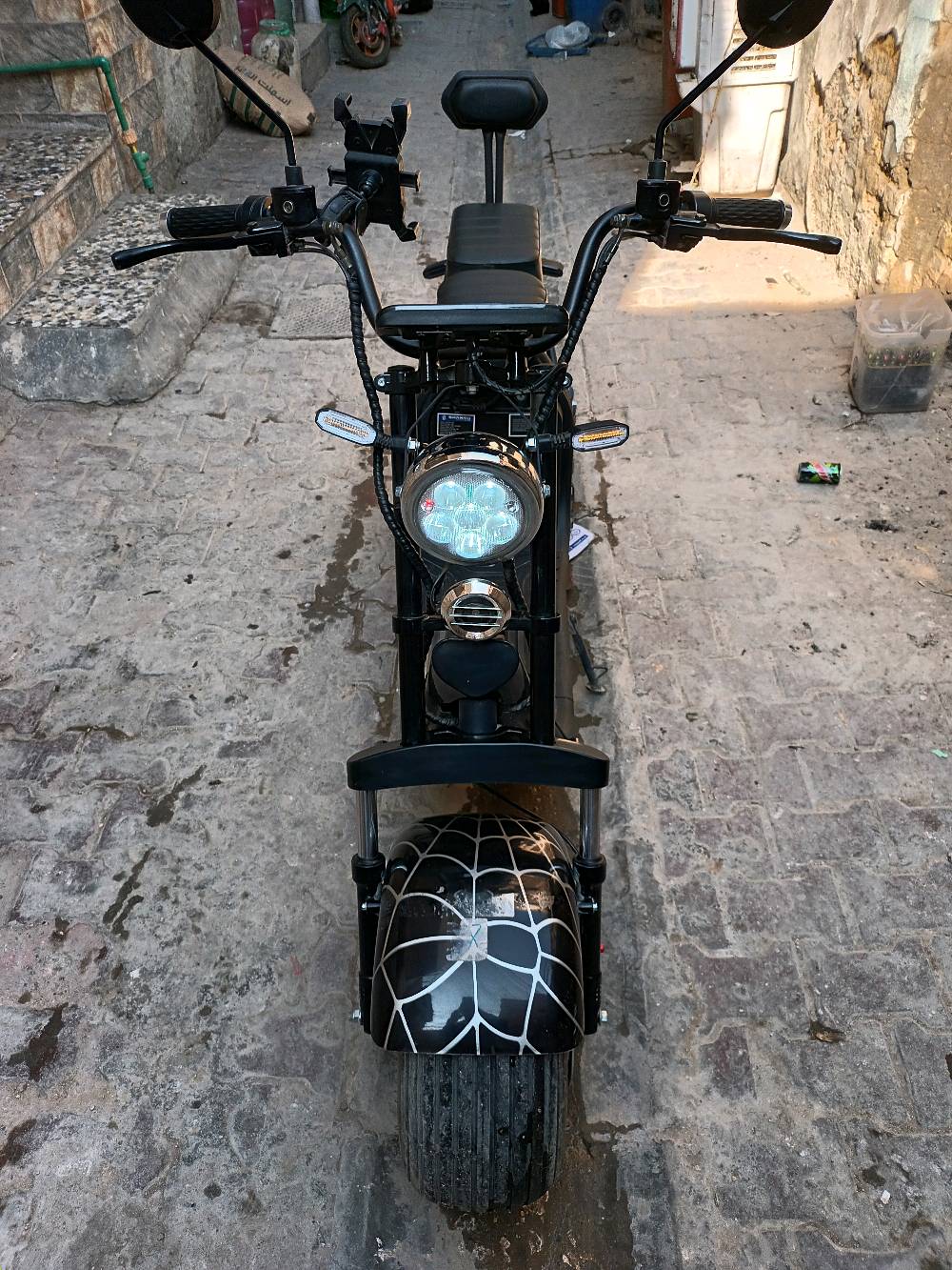 ماطور كهربائي جديد وحديث التصميم بهيكل قوي وعجلات عريضة تعطي استقرار وثبات. يحتوي على مقعدين مريحين ومُصمم بتفاصيل مميزة بنمط يشبه شبكة العنكبوت على العجلات. مثالي للتنقل السريع والبيئي داخل المدينة.