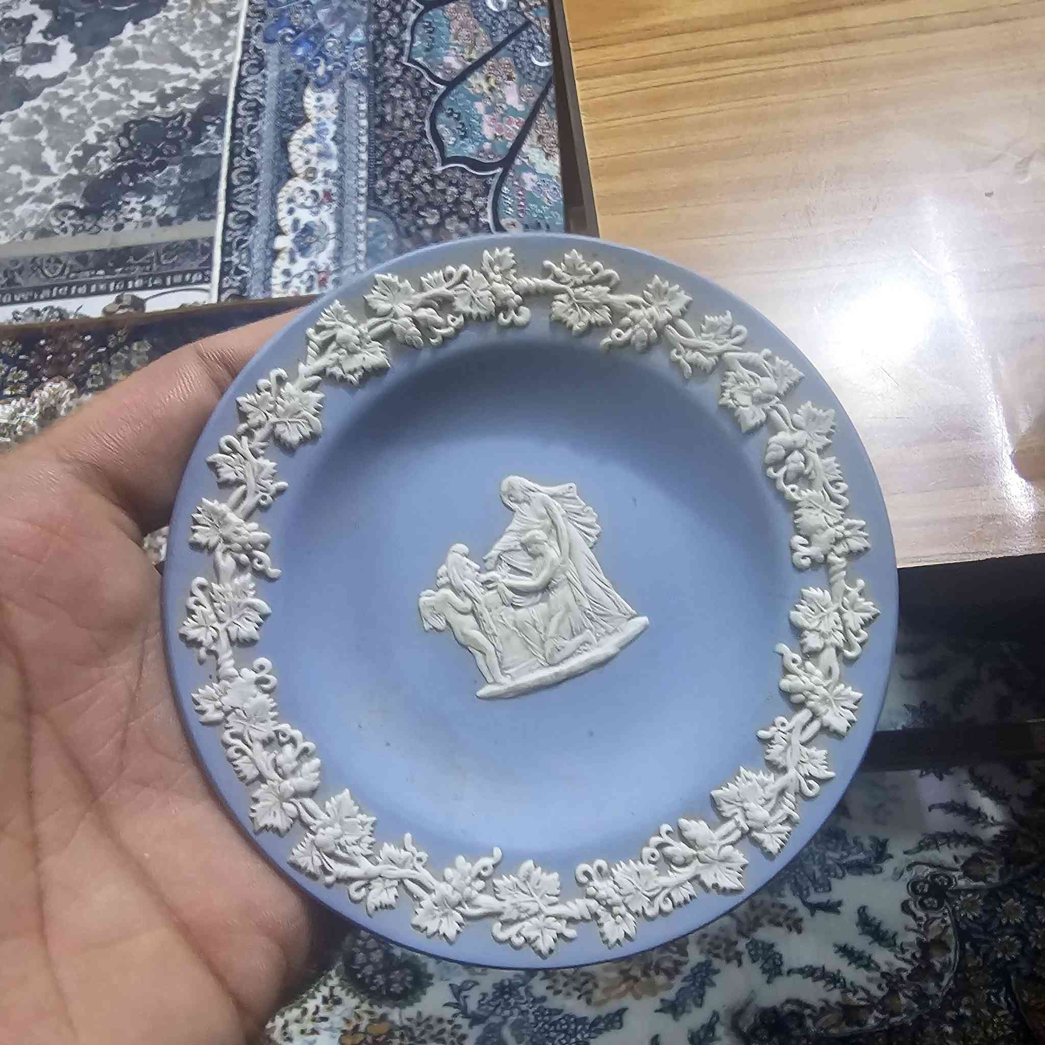 هذا الصحن هو قطعة فنية من فخار جاسبر وير (Jasperware) الشهير
من إنتاج شركة ويدجوود (Wedgwood) البريطانية العريقة.
​إليك التفاصيل حول هذه القطعة:
​ما هو هذا الشيء؟
​النوع: يُعرف بـ "جاسبر وير" باللون الأزرق الفاتح (Pale Blue Jasperware).
​التصميم: يتميز بالنقوش البيضاء البارزة المصنوعة من الكامي أو البورسلين، والتي عادة ما تصور مشاهد كلاسيكية أو أسطورية مستوحاة من الفن اليوناني والروماني القديم.
​الاستخدام: يُستخدم كقطعة ديكور أو صحن صغير للزينة (Trinket Dish).
​إلى أي سنة يعود؟
​بناءً على الختم الموجود في خلفية الصحن (WEDGWOOD - MADE IN ENGLAND):
​الفترة الزمنية: كلمة "MADE IN ENGLAND" بدأت الشركة باستخدامها بعد عام ١٩٠٨ 

 قطعة أصلية من إنتاج المصنع في إنجلترا وليس تقليداً


**إذا كنت صاحب هذا الإعلان وتريد حذفه لأي سبب، رجاءا أرسل رسالة إلى الدعم الفني**