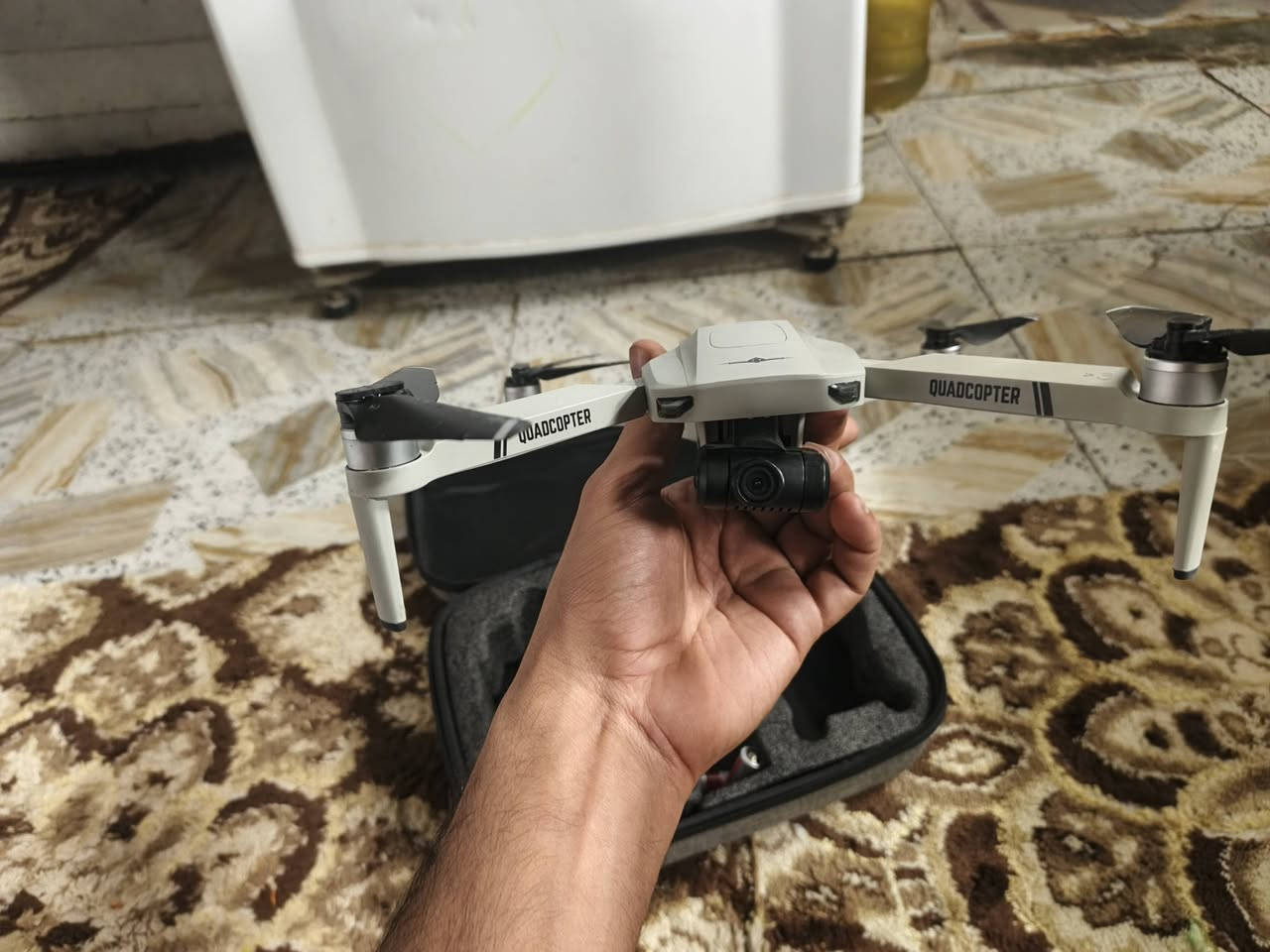 اسلام عليكم
بناءً على الصورة والبحث، هذه هي طائرة الدرون KF102 (أو KF102 MAX)، وهي طائرة قابلة للطي مزودة بنظام تحديد المواقع (GPS) وكاميرا بدقة 4K مثبتة على جيمبال (محور استقرار) ثنائي المحاور. 
المكونات والملحقات الظاهرة في الصورة:
طائرة الدرون: جسم الطائرة القابل للطي في الجهة اليمنى.
جهاز التحكم عن بعد: مزود بشاشة LCD لعرض بيانات الرحلة وحامل للهاتف الذكي.
نظارات VR (الواقع الافتراضي): نظارات FPV سوداء تتيح لك رؤية ما تصوره الكاميرا وكأنك داخل الطائرة.
البطاريات: يظهر في الصورة 3 بطاريات إضافية (7.4 فولت، 2200 مللي أمبير)، مما يطيل وقت الطيران الإجمالي.
حقيبة التخزين: حقيبة مخصصة لحماية الطائرة وملحقاتها وسهولة نقلها. 
أبرز المواصفات والمميزات:
التصوير: كاميرا 4K مع محور استقرار ثنائي المحاور لتقليل الاهتزاز وضمان فيديو سلس.
نظام الطيران: محركات "برشلس" (Brushless) قوية ومقاومة للرياح، مع مدى تحكم يصل إلى 800-1200 متر.
وقت الطيران: تستمر البطارية الواحدة لحوالي 22-25 دقيقة.
ميزات ذكية: تدعم "العودة التلقائية" عند انخفاض البطارية، "المتابعة الذكية" (Follow Me)، والطيران عبر مسار محدد مسبقاً على الخريطة.
تجنب العوائق: إصدار KF102 MAX قد يحتوي على مستشعر لتجنب العوائق بزاوية 360 درجة.


**إذا كنت صاحب هذا الإعلان وتريد حذفه لأي سبب، رجاءا أرسل رسالة إلى الدعم الفني**