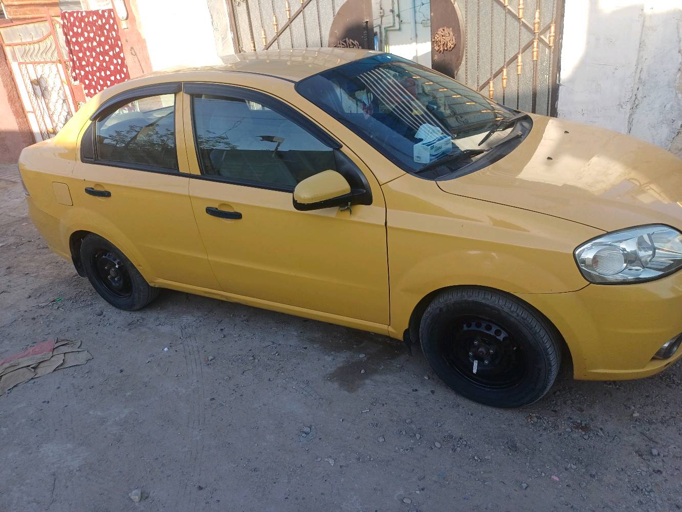 سيارة شيفروليه صفراء، مناسبة للعمل كسيارة أجرة. حالتها الخارجية جيدة مع بعض الخدوش البسيطة. السيارة نظيفة من الداخل ومُجهزة بمقاعد مريحة. المكان بغداد، واللوحات تشير إلى أنها مُرخصة كسيارة أجرة.