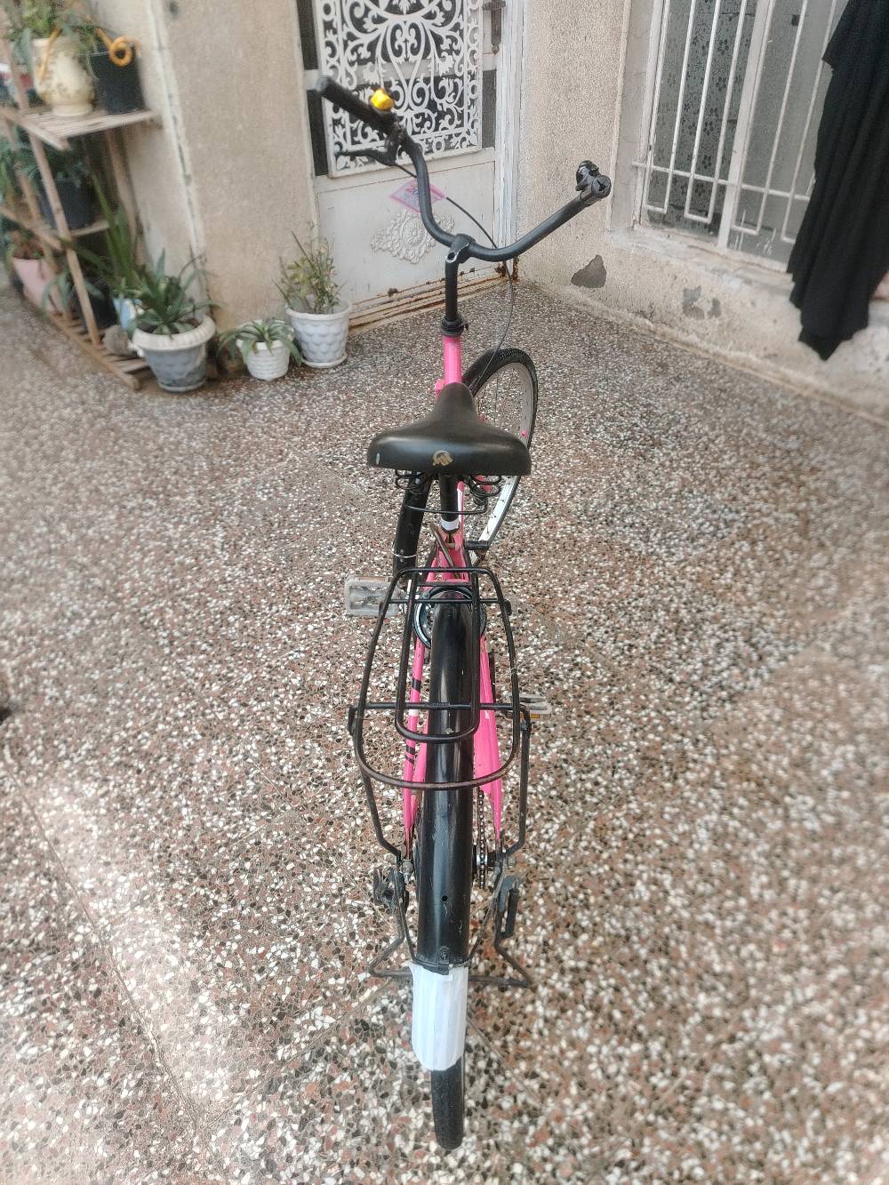 بايسكل وردي جميل بحالة جيدة مع جرس، مثالي للنزهات والتجول في المدينة. يتميز بهيكل متين وكرسي مريح.