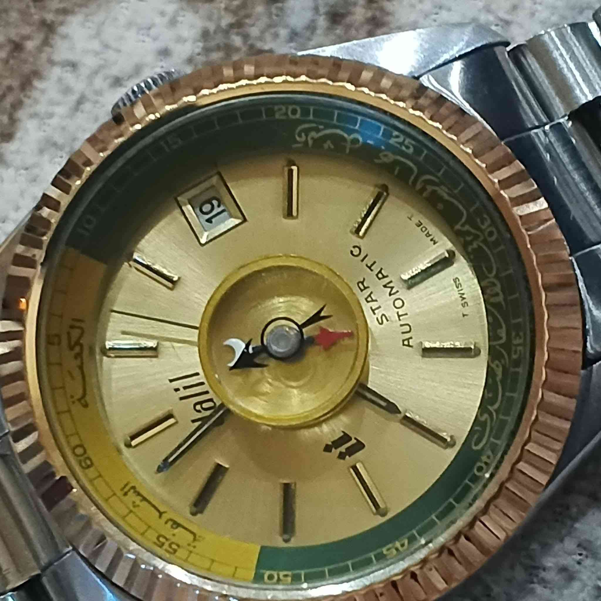 ساعة "دليل" الأوتوماتيكية (Dalil Star Automatic)، وهي ساعة سويسرية كلاسيكية نادرة صُنعت في فترة السبعينيات والثمانينيات خصيصاً للمسلمين لتساعدهم على تحديد اتجاه القبلة وتتبع مواقيت الصلاة أثناء السفر. [1, 2]
ساعة دليل السويسرية الأوتوماتيكية الأصلية للقبلة (Dalil Star Automatic)، وهي ساعة كلاسيكية نادرة (Vintage) تعود لفترة السبعينيات والثمانينيات، وصُنعت خصيصاً لمساعدة المسلمين في تحديد اتجاه القبلة. 
·كروب عدي الحميداوي لبيع وشراء الانتيكات والنحاسيات والاجهزة الصوتية القديمة
 +1
أبرز مواصفات ومميزات الساعة:
بوصلة مدمجة: تحتوي على بوصلة في منتصف الميناء مخصصة لتحديد اتجاه مكة المكرمة (القبلة).
الصناعة والمنشأ: صناعة سويسرية أصلية بالكامل (Swiss Made) وتتمتع بجودة عالية.
حركة الساعة: تعمل بنظام الحركة الميكانيكية الأوتوماتيكية (Self-Winding) التي تعتمد على حركة معصم اليد.
التصميم والميناء: تتميز بإطار مضلع ذهبي اللون، ويحيط بمينائها الذهبي حلقة بلون أخضر نُقش عليها أسماء دول وعبارات باللغة العربية.
القيمة التراثية: تُعد هذه الساعة اليوم من المقتنيات النادرة والقطع الأثرية الثمينة التي يبحث عنها هواة جمع الساعات القديمة


**إذا كنت صاحب هذا الإعلان وتريد حذفه لأي سبب، رجاءا أرسل رسالة إلى الدعم الفني**