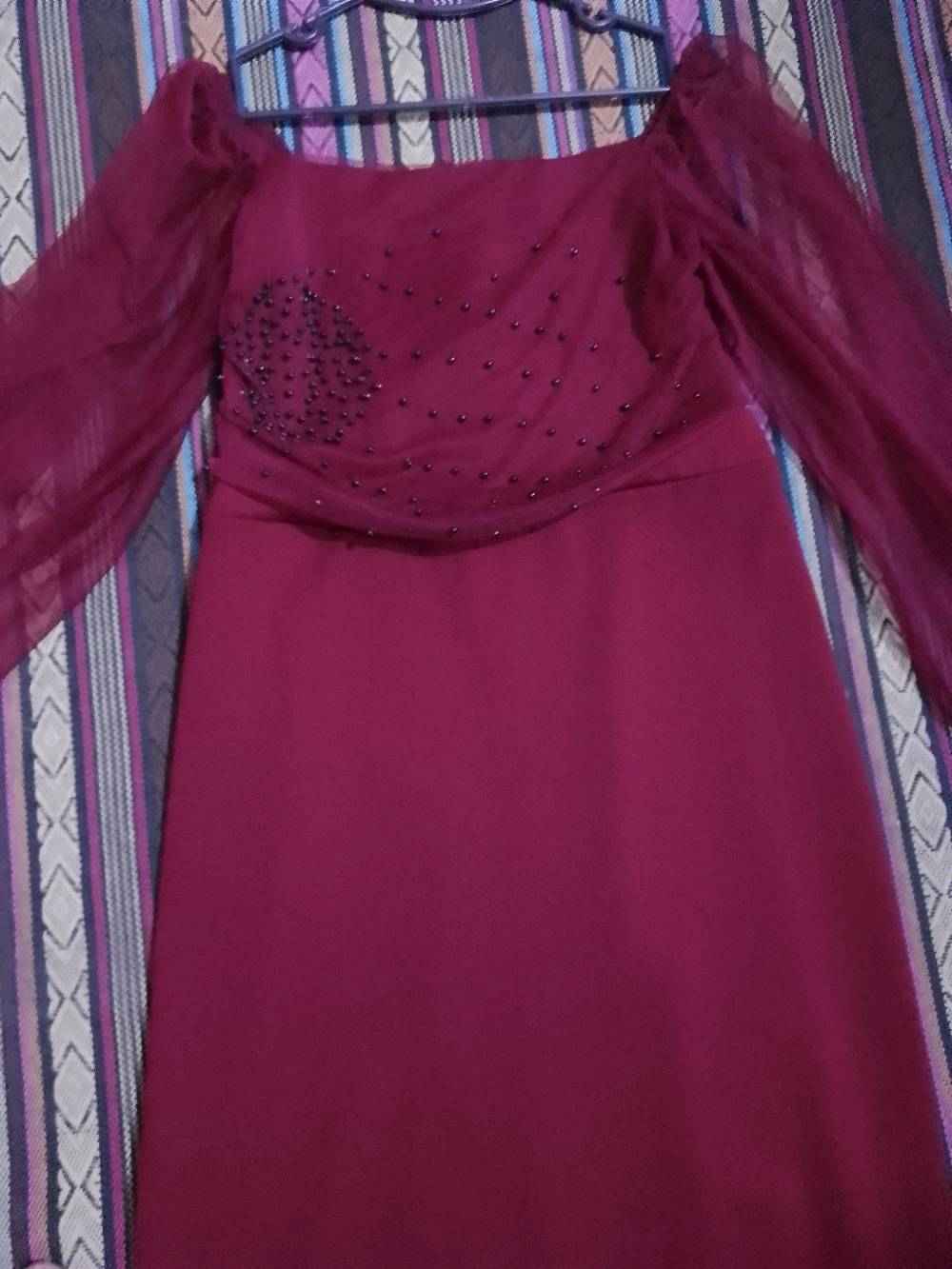 فستان أنيق بتصميم مميز باللون العنابي مع أكمام شفافة وتطريز لؤلؤي على الجزء العلوي. مثالي للمناسبات الخاصة والاحتفالات. يتميز بخامة ناعمة تضمن الراحة أثناء الارتداء.